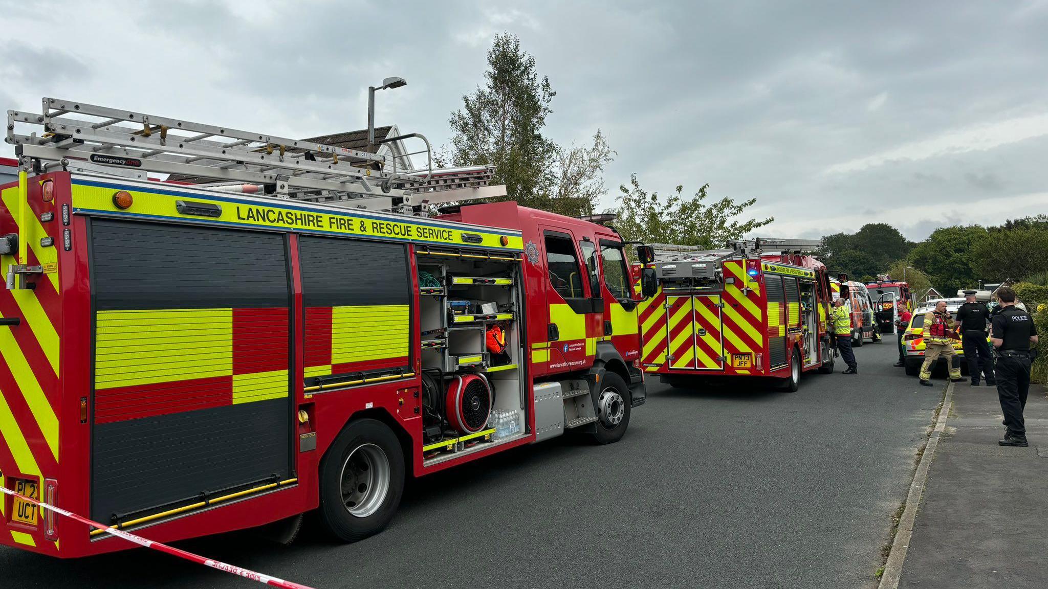 Fire vehicles behind emergency service tape as workers attend the scene on Wheatley Drive 