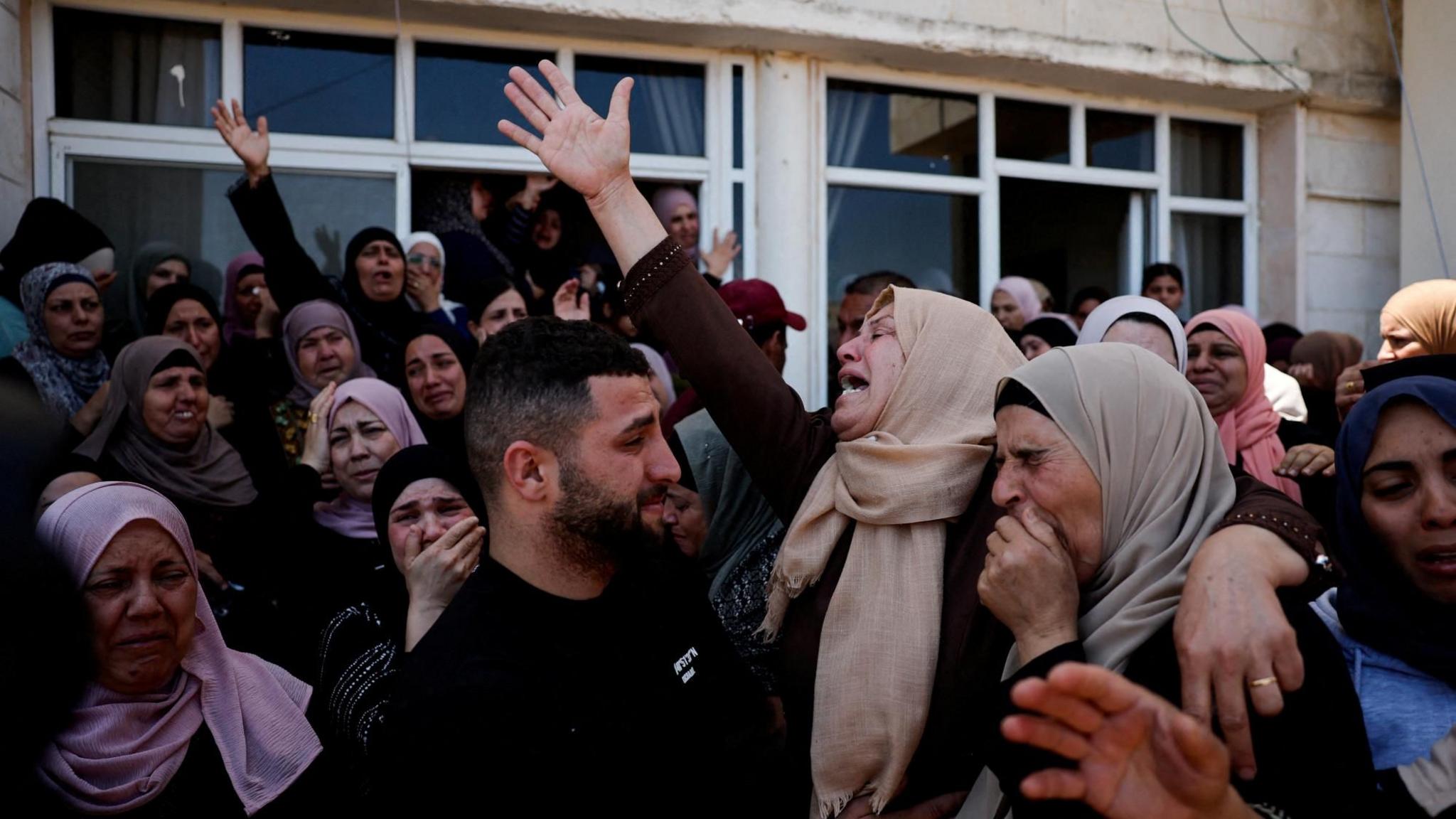 Mourners react during the funeral of Palestinian men who were killed during an attack by Israeli settlers in Kafr Malik, in the Israeli-occupied West Bank (25 June 2025)