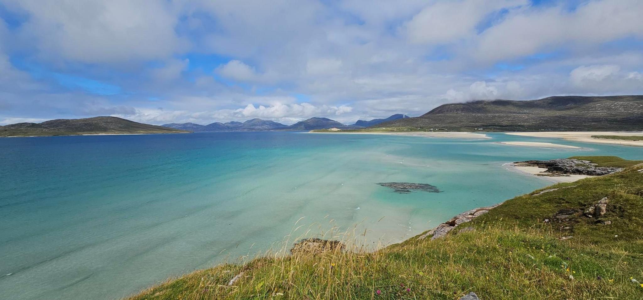 A bay with an ombre blue effect sea taken from the hills above the beach