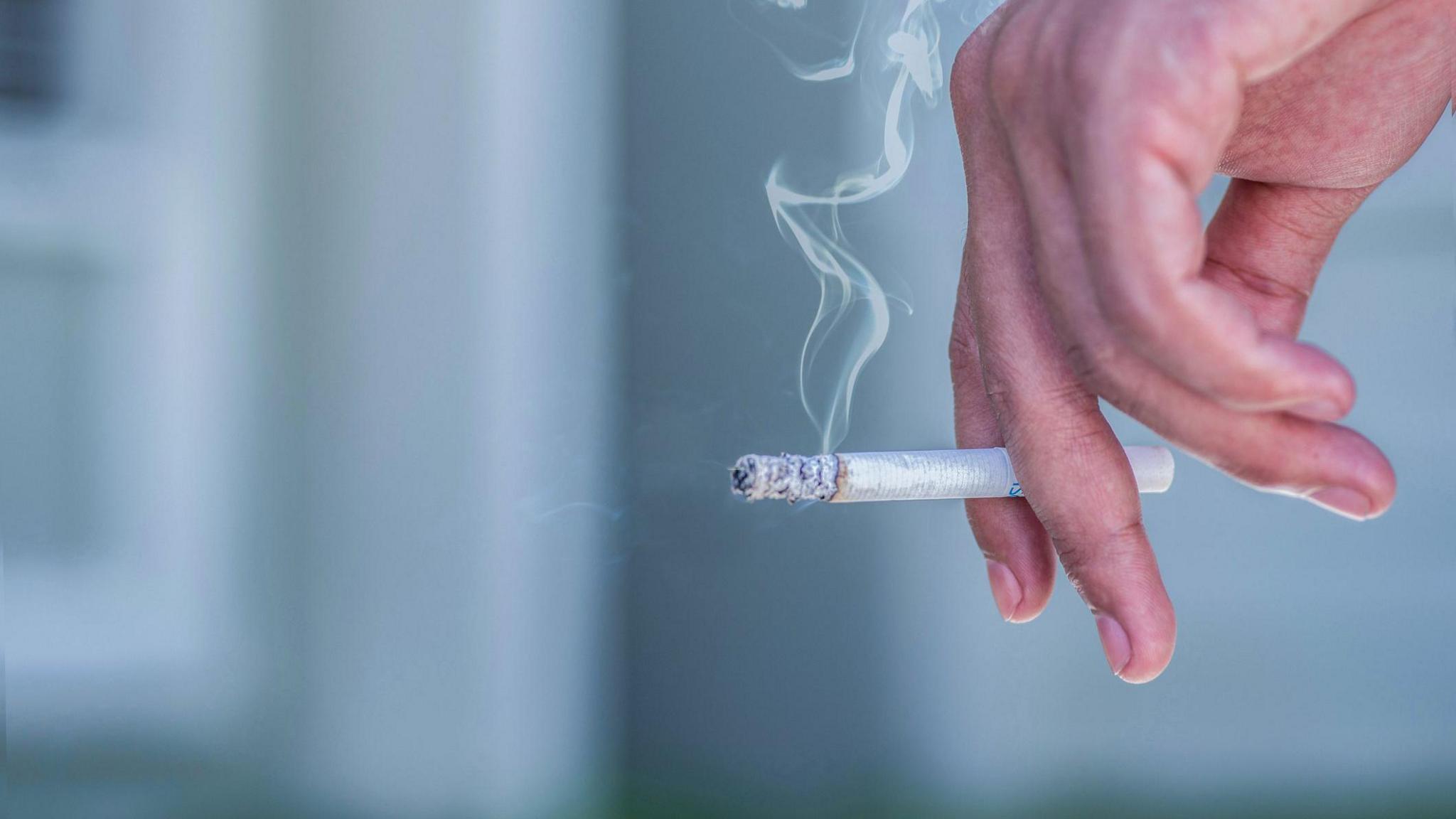A hand holding a lit cigarette