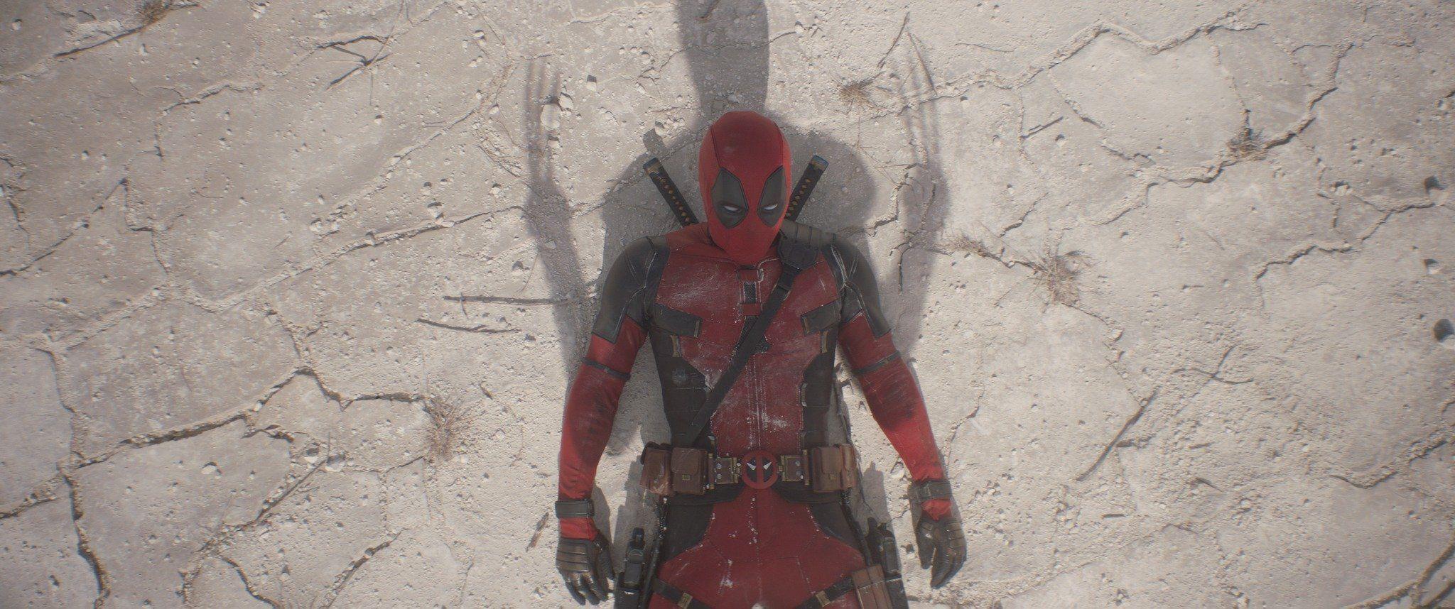 Deadpool knocked to the ground as the shadow of Wolverine's claws tower over him