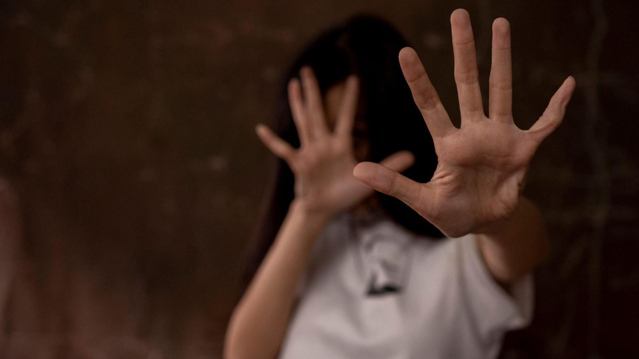 Women puts her hands up to shield herself - stock photo from Getty