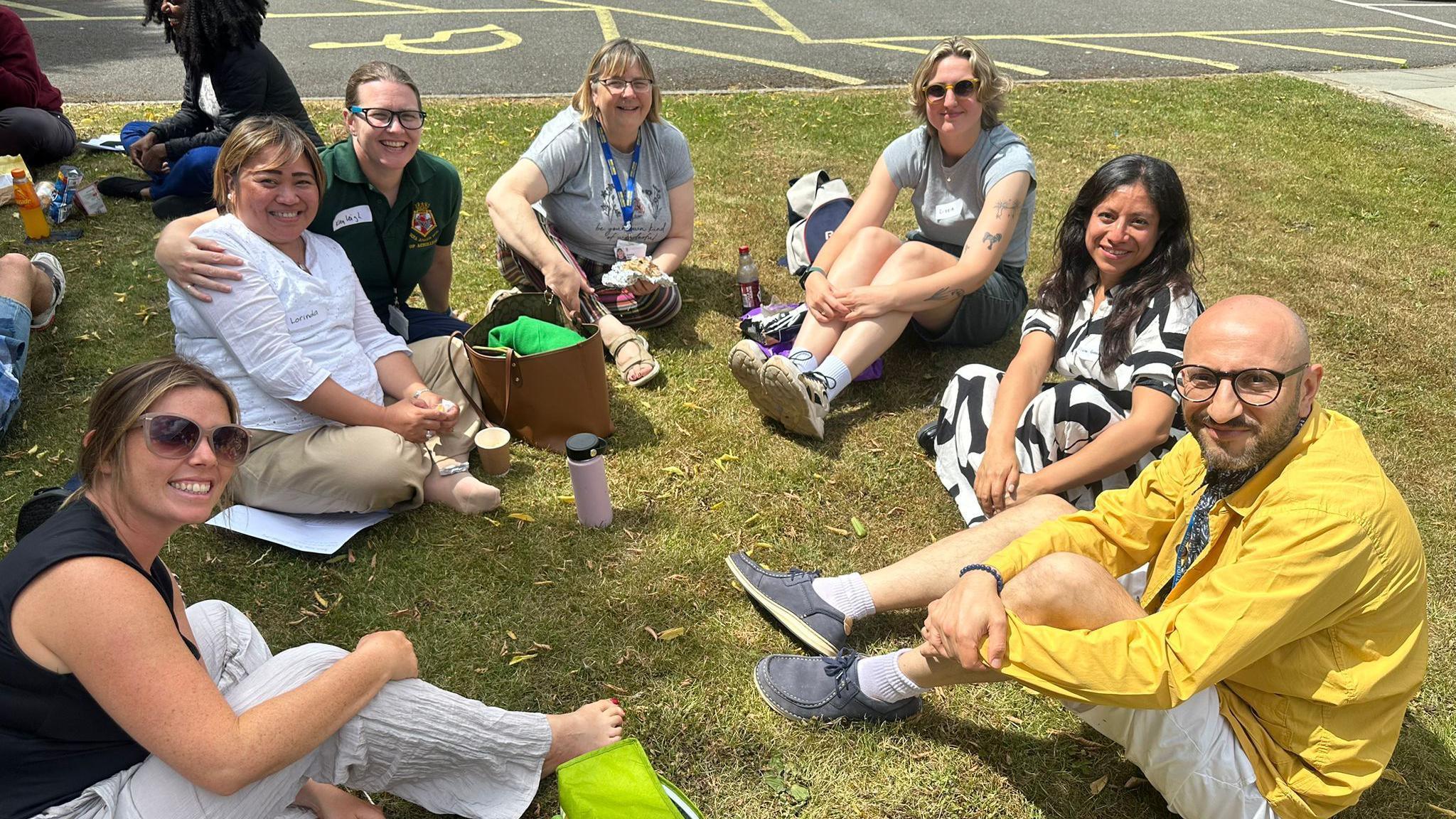 A group of students sitting in a semi circle on a grass bank