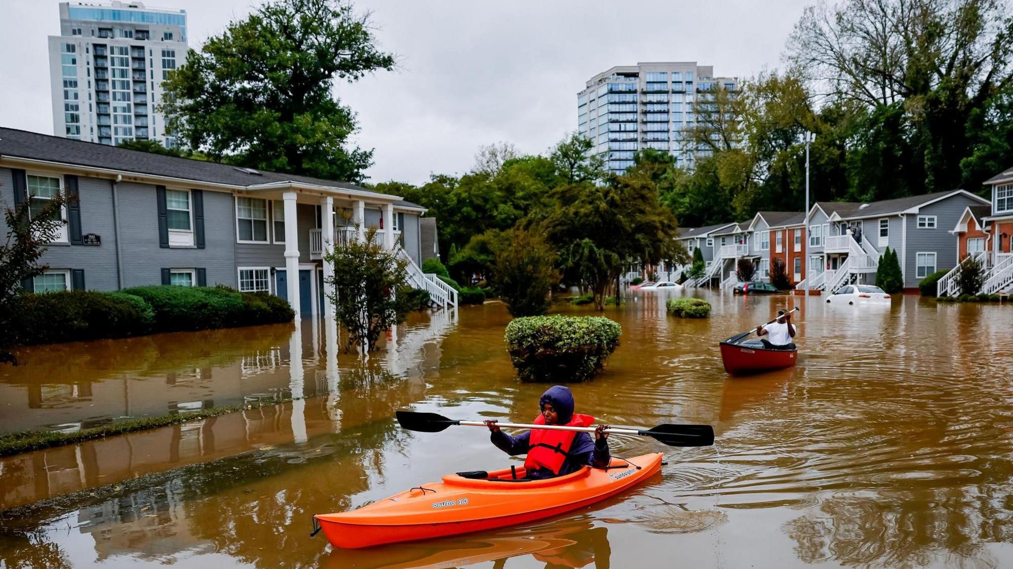 Peachtree Park Apartments resident Candice Ocvil (left) and Jibri Tolenrow through flood waters from Peachtree Creek, Georgia