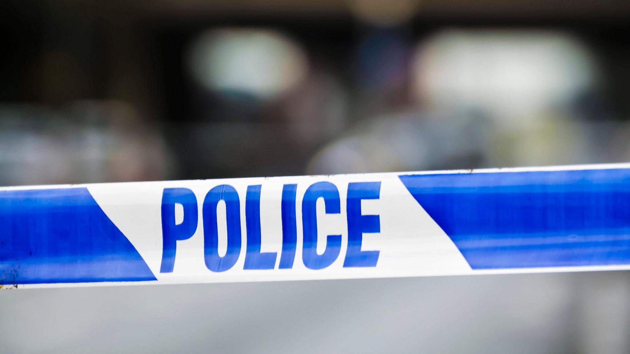 Stock image of a blue and white police cordon. The background is blurred.