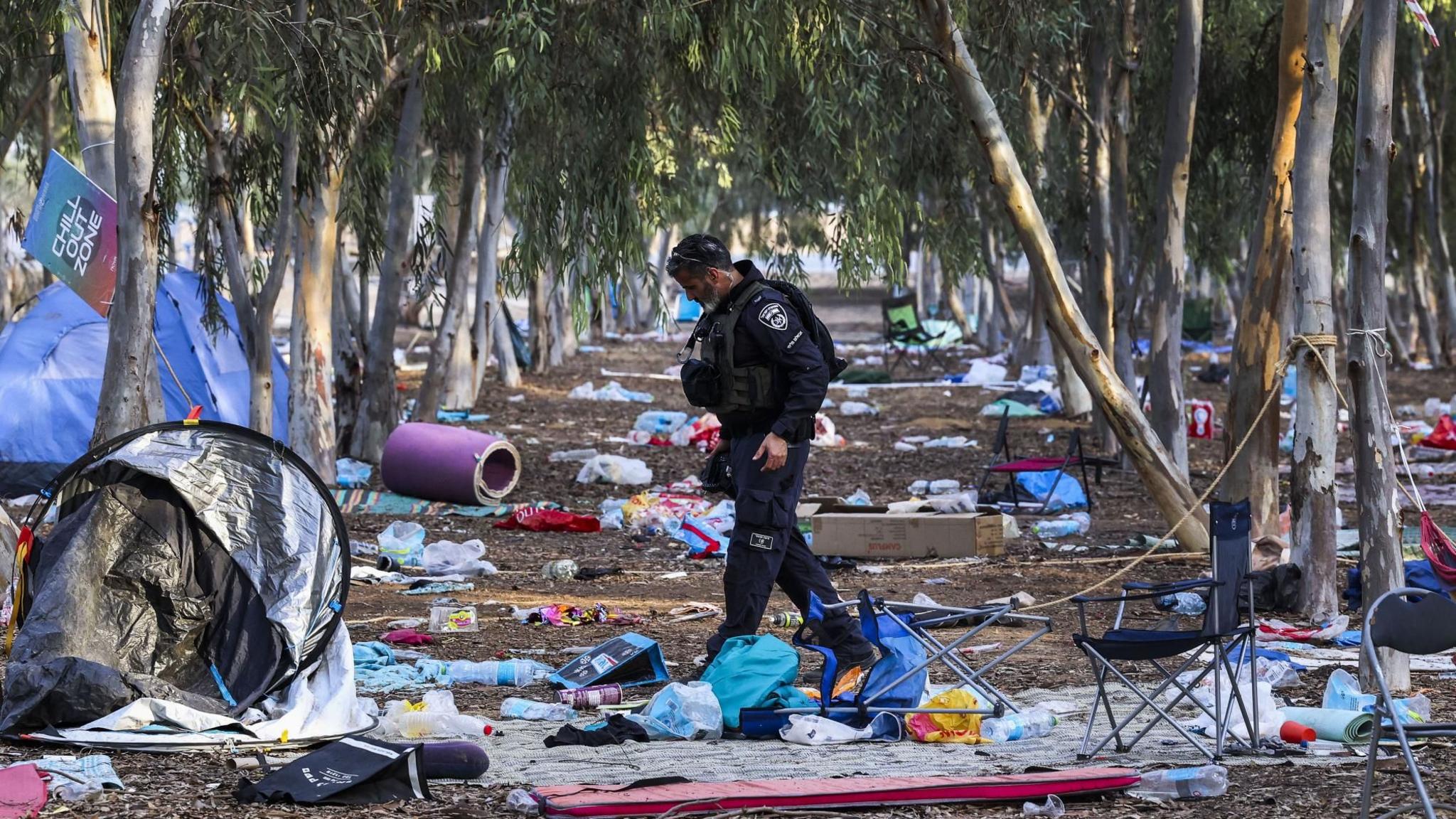 An Israeli officer walks at the site of the Supernova music festival, in southern Israel, after the killing of hundreds of Israeli civilians by Hamas-led gunman (17 October 2023)