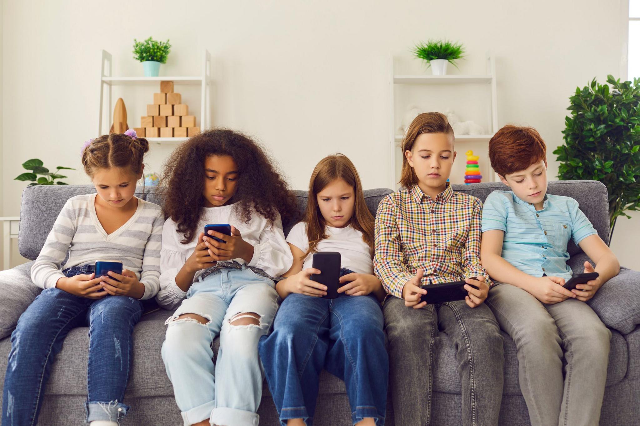 group of children seated and using phones. 