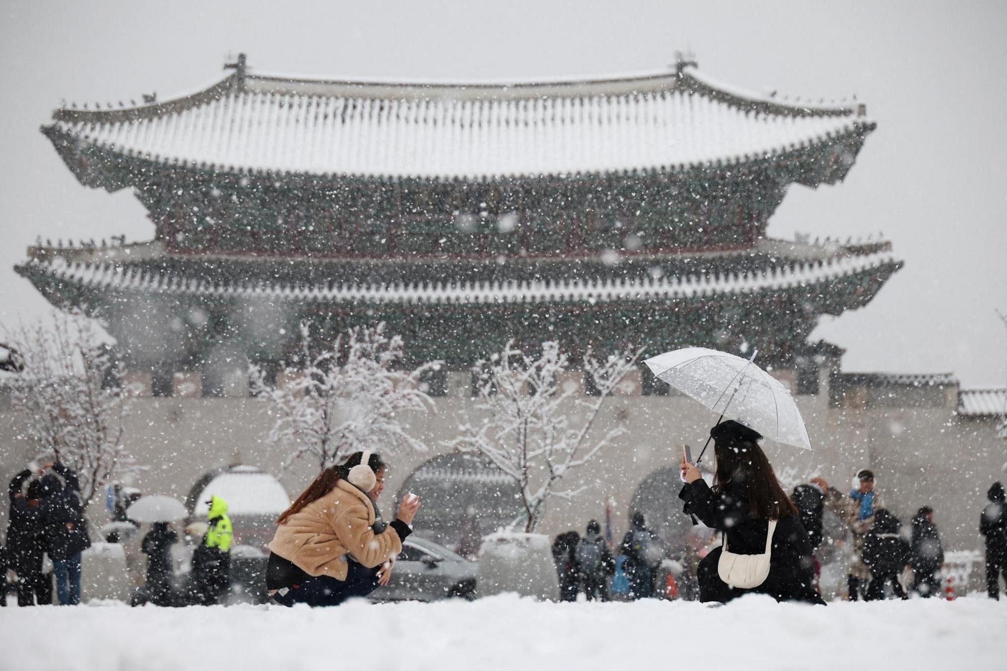 A woman takes a photographs of her friend during heavy snow fall in central Seoul 
