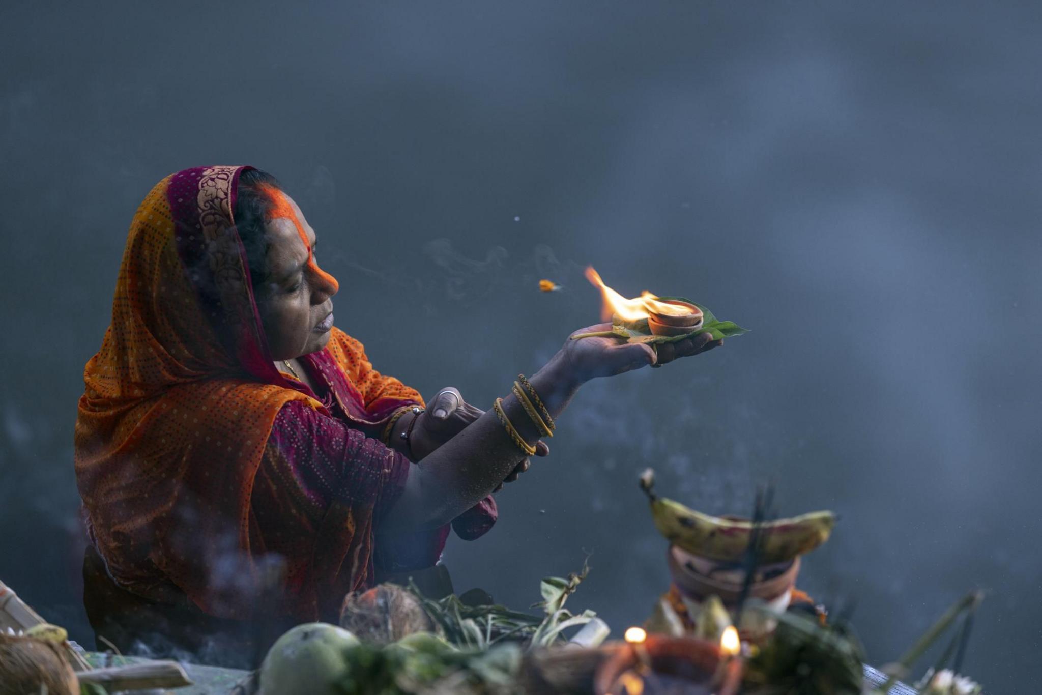 A Nepalese Hindu devotee wearing wedding attire and ornaments attends an evening prayer during the Chhath festival at Kamal Pokhari Pond in Kathmandu