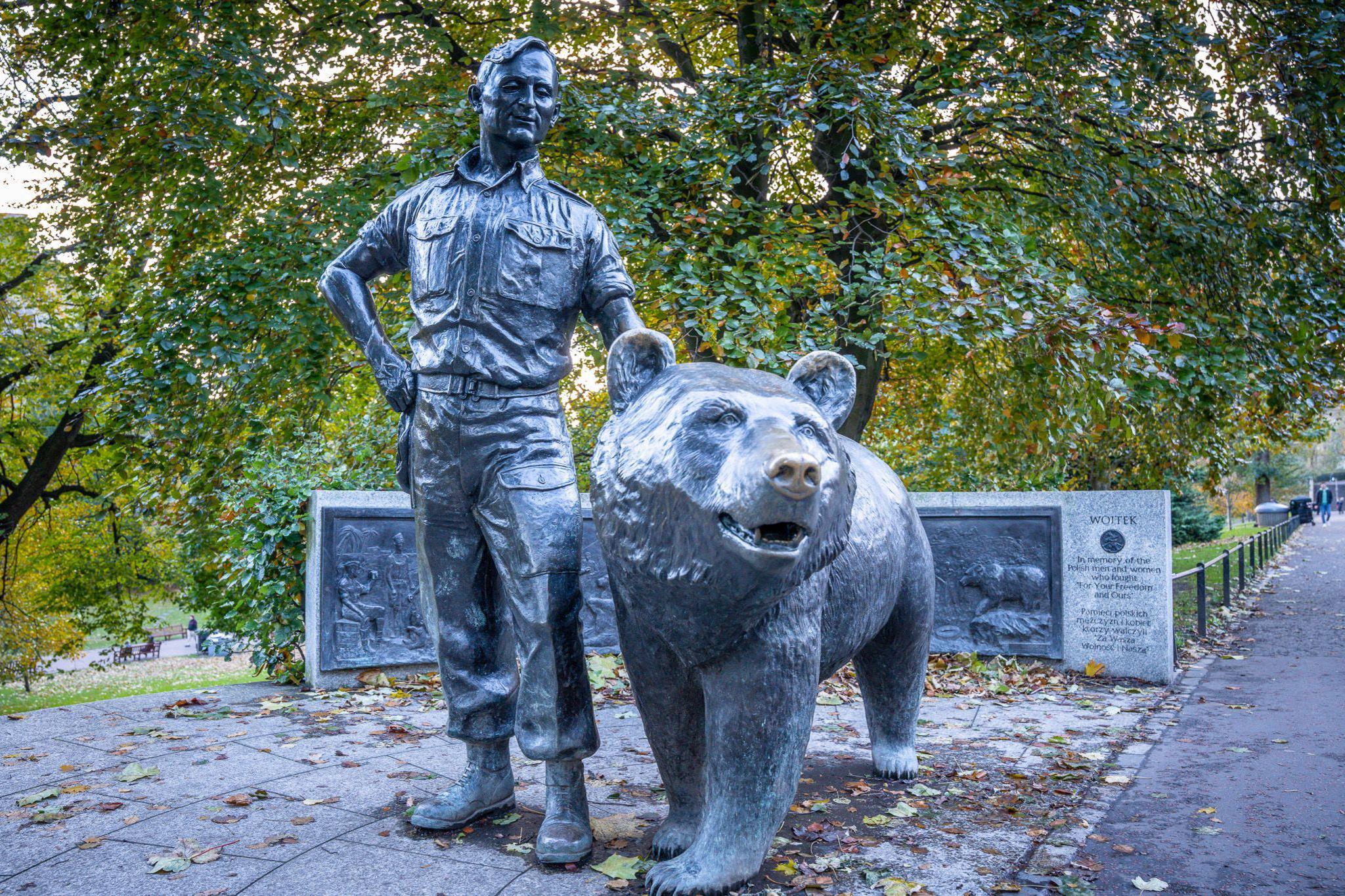 A bronze cast of Wojtek the bear next to a Polish soldier stands in front of a bronze and granite plaque in Princes Street Gardens, Edinburgh.