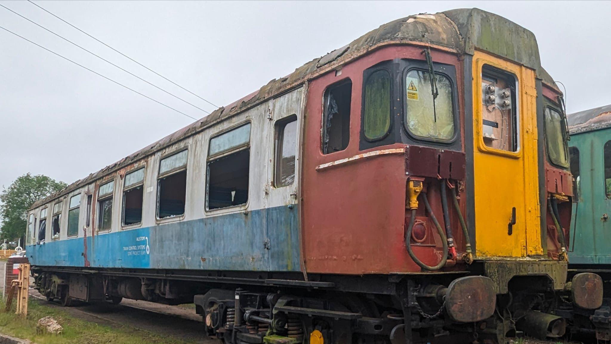 A view of the Clacton Express train prior to its restoration. It is missing its side passenger windows and its paintwork is heavily faded and dull. 