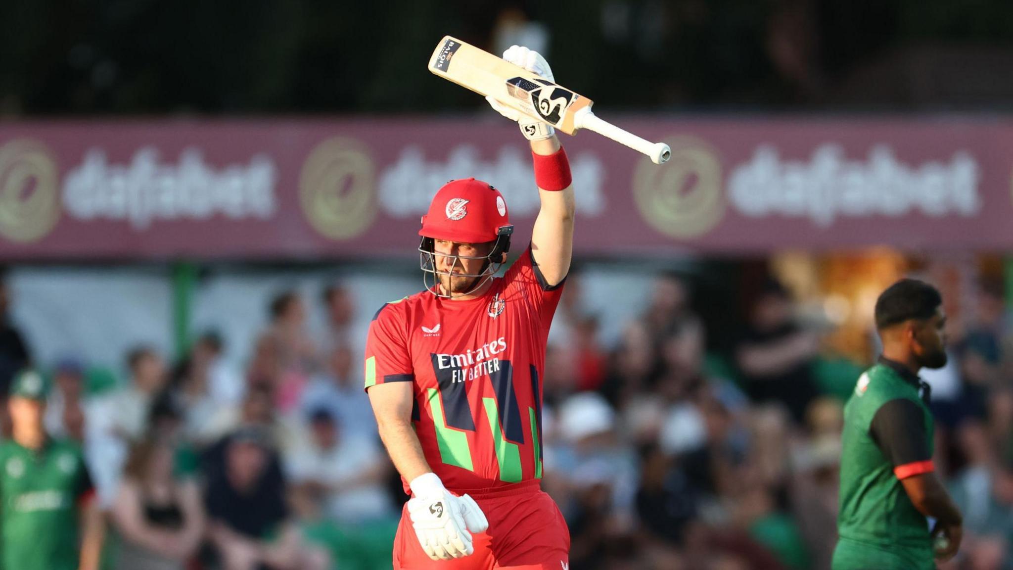 Lancashire Lightning batsman Liam Livingstone holding his bat aloft in his left hand after hitting a half-century.