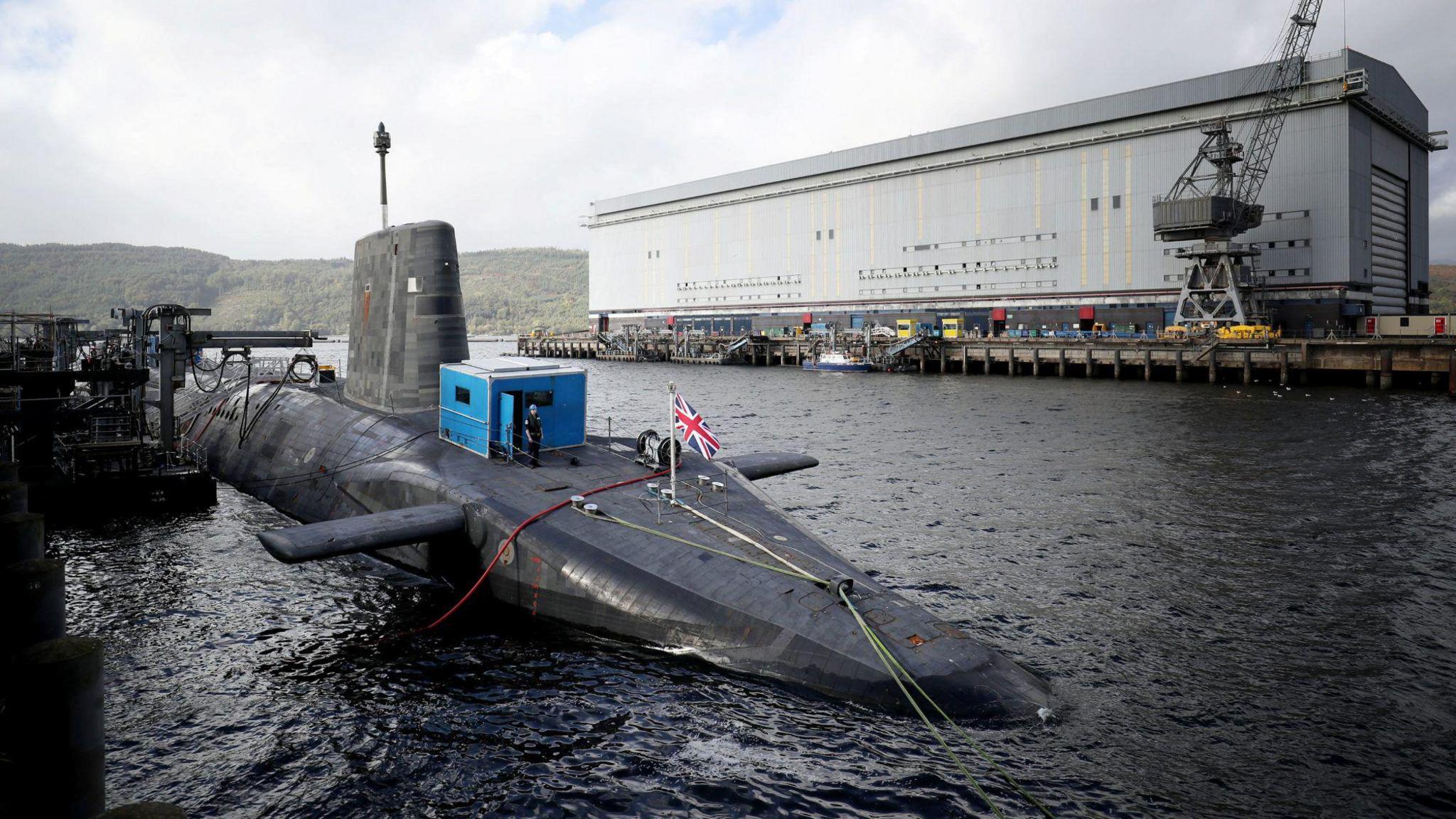 A Vanguard class submarine in dock at Faslane. A submariner in uniform can be seen on the deck