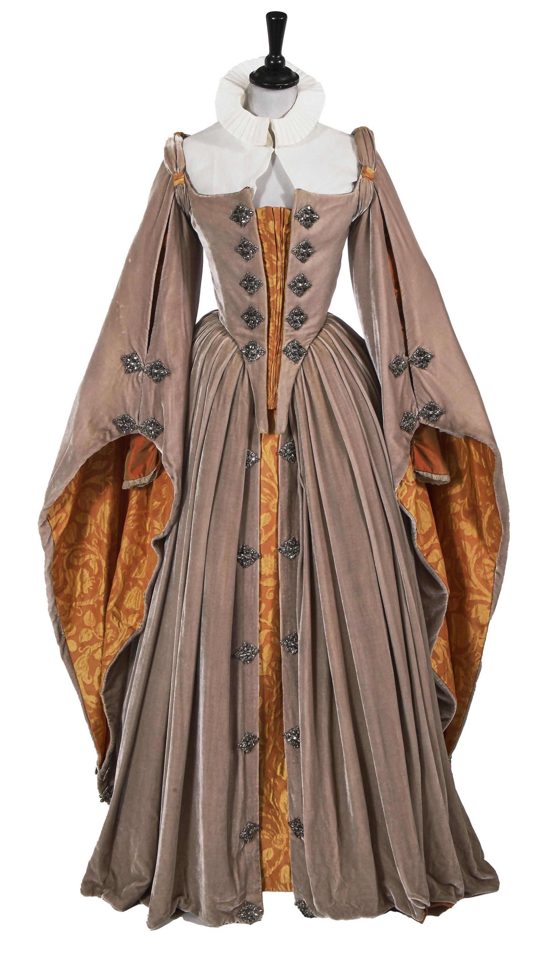 A mid-16th-century-inspired gown of taupe velvet, split-front bodice trimmed with cut-steel medallions, long dramatic Spanish split-sleeves with orange shot silk undersleeve and orange and yellow brocade lining, a full gathered skirt with split front, lined in orange shot silk.