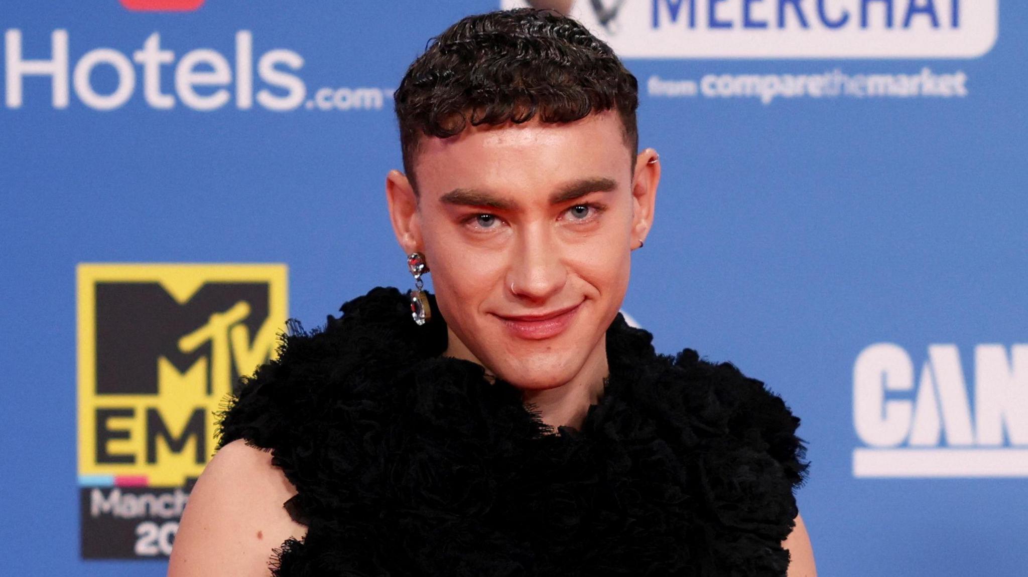 Olly Alexander in front of a blue background on the MTV Awards red carpet