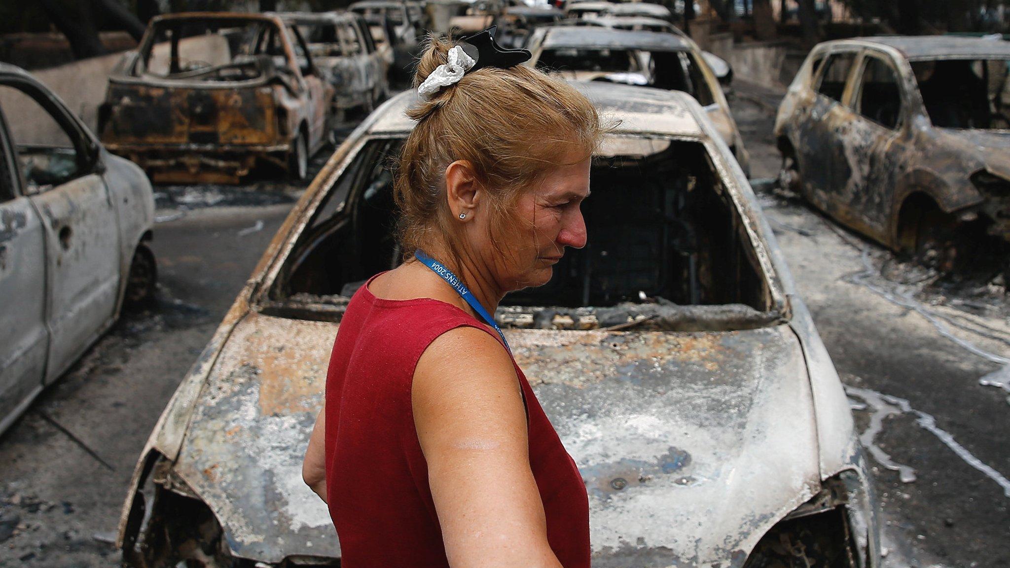 A local stands next to burnt cars following a wildfire at the village of Mati, near Athens, Greece, 24 July 2018