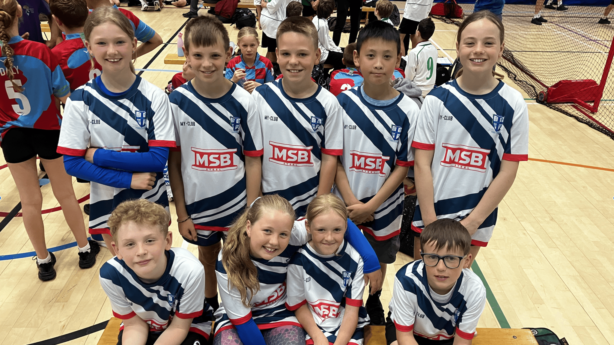 Five boys and four girls from St Whites school. They are all huddled together looking into the camera smiling.