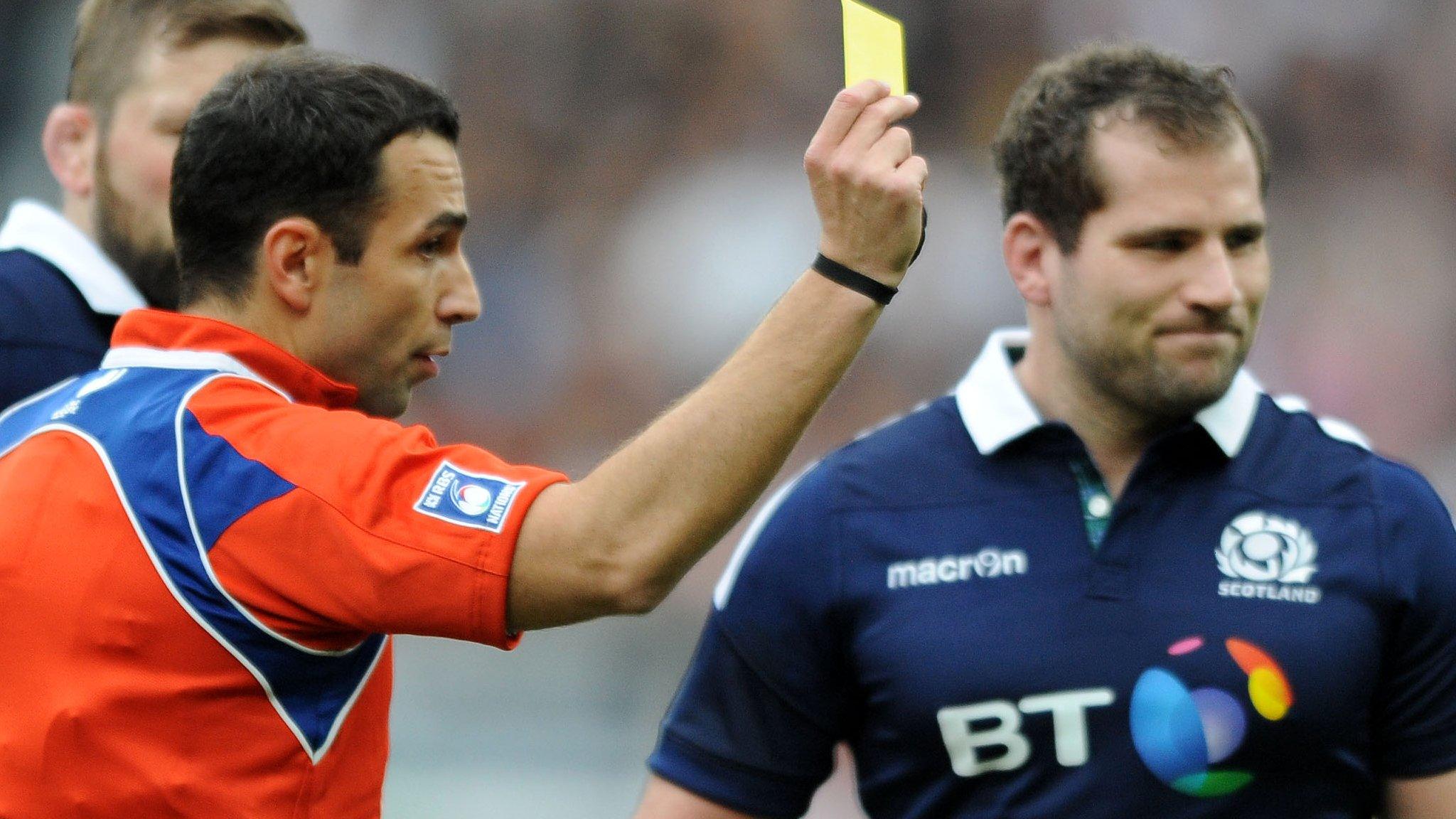 Referee Mathieu Raynal shows Fraser Brown the yellow card