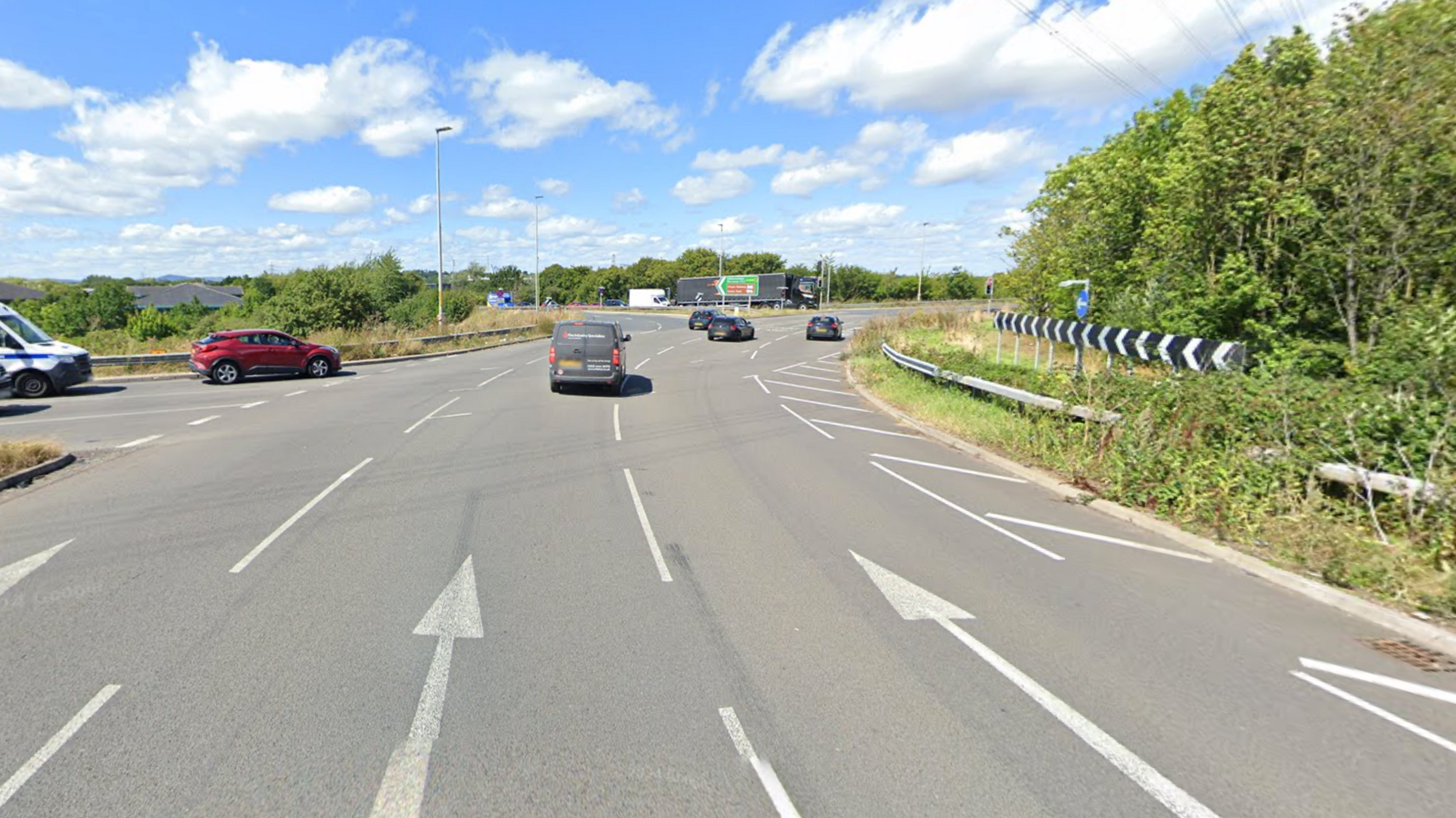 A street view of the Sixways roundabout with three lanes for cars. Four black cars are driving on the roundabout and a red car is turning onto the roundabout