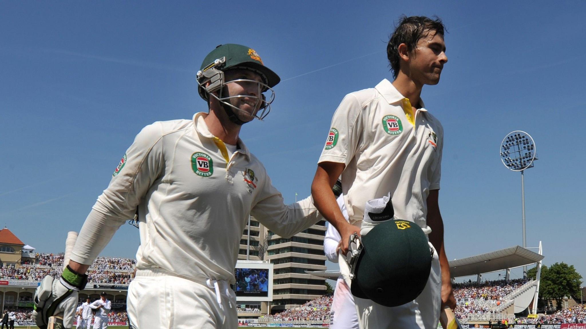 Ashton Agar, holding his helmet, walks off with Phillip Hughes