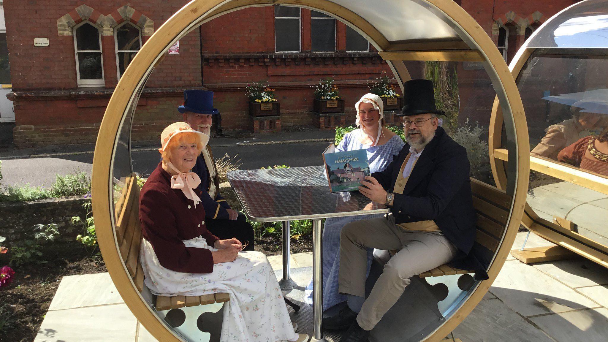 Members of the Jane Austen Regency Week Committee in the new Memorial Garden in Alton sat inside a carriage bench