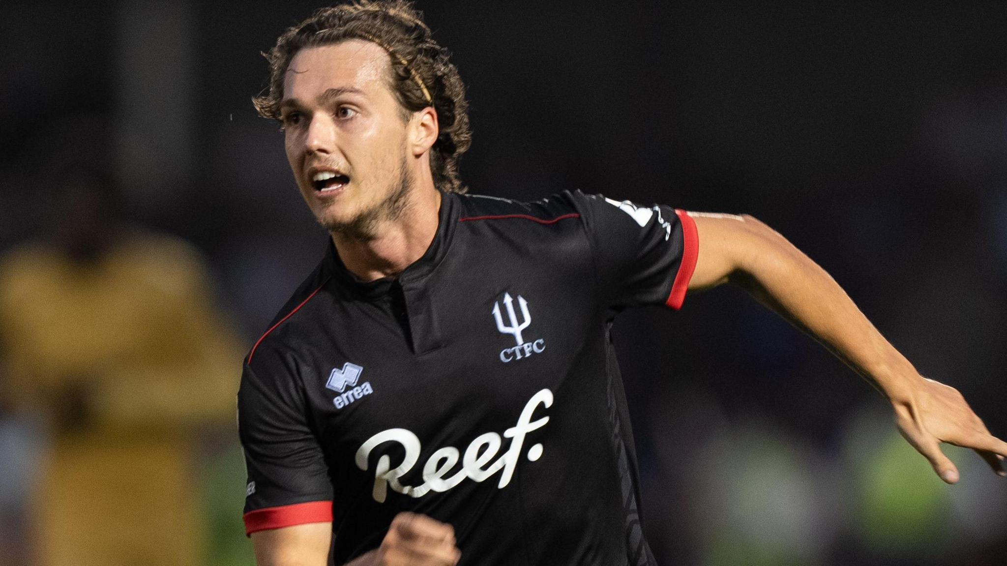 Harry Forster running in black Crawley Town away kit with his left arm out