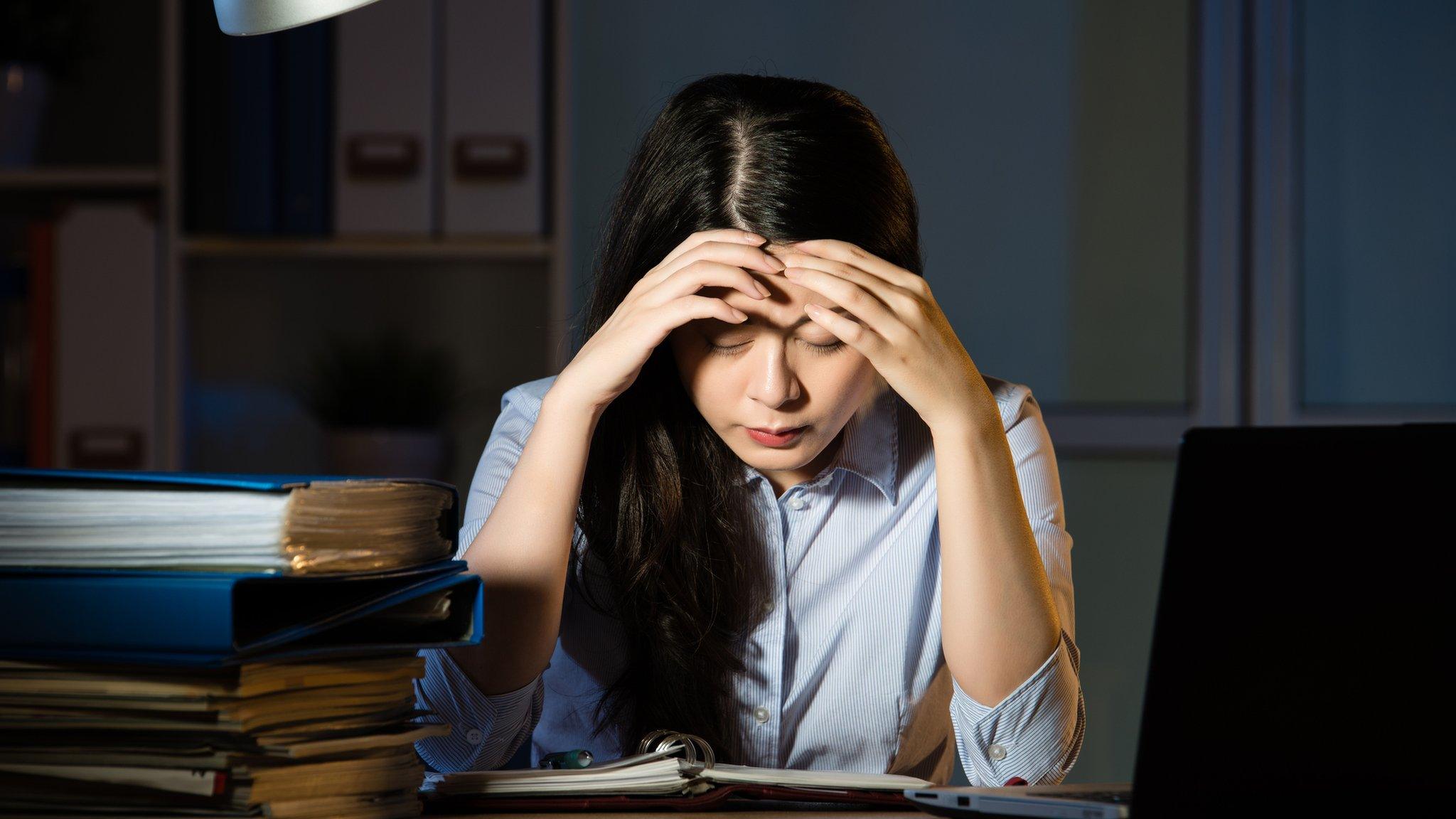 Woman at work with her head in her hands