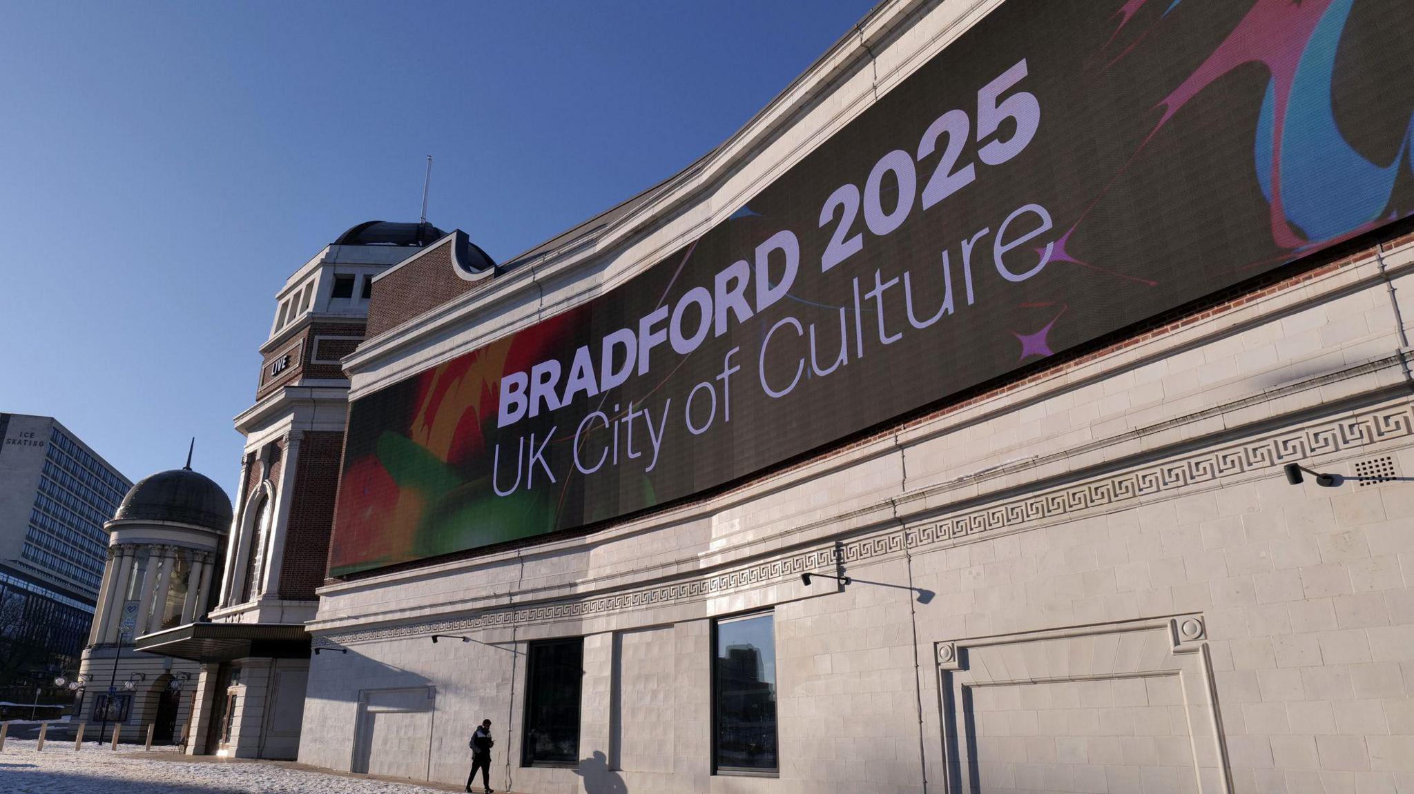 Large vibrant electronic sign shows Bradford's designation for the UK City of Culture set on the facade of the Bradford Live entertainment venue.