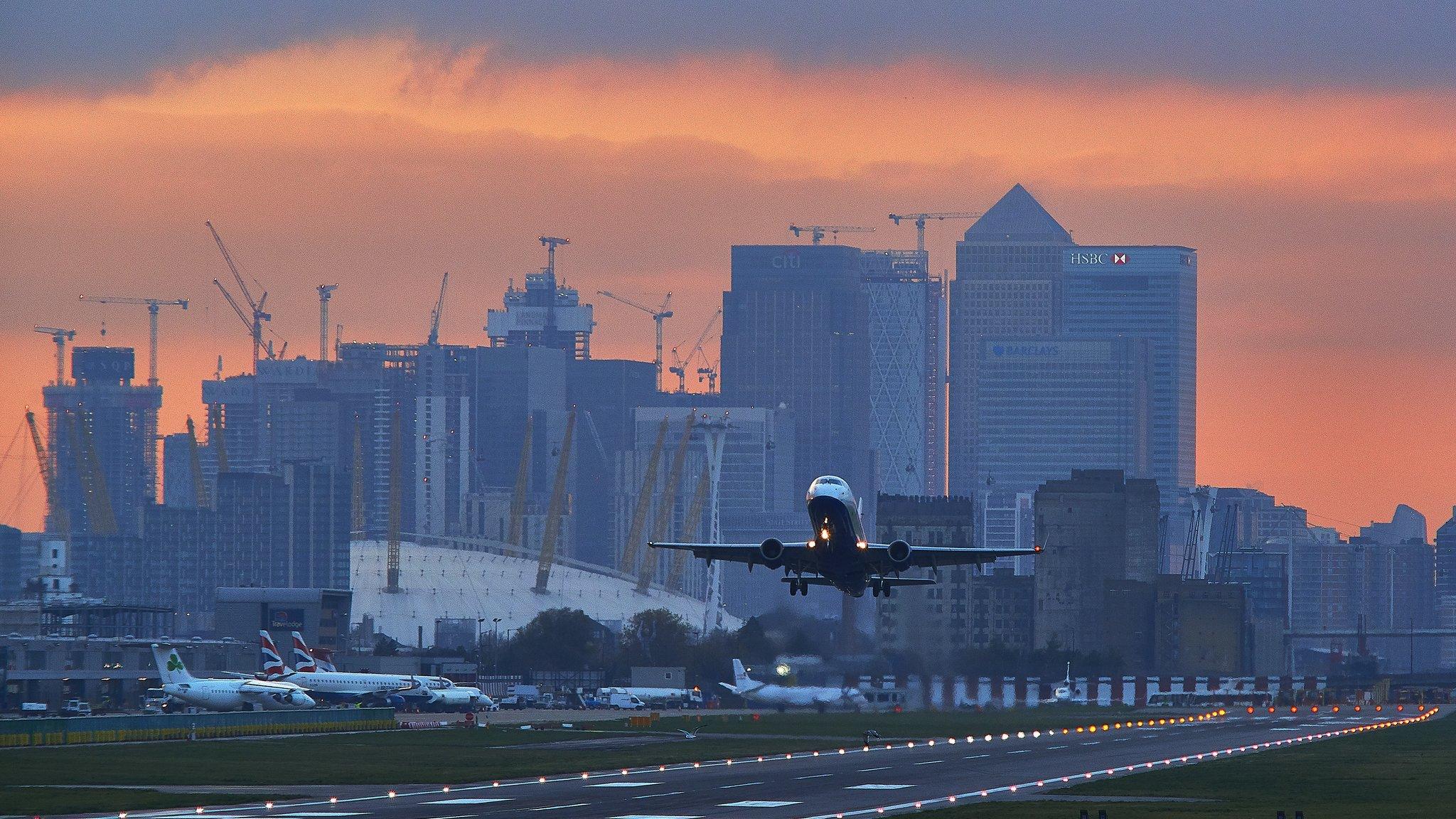 Plane takes off from London City Airport with Canary Wharf in the background