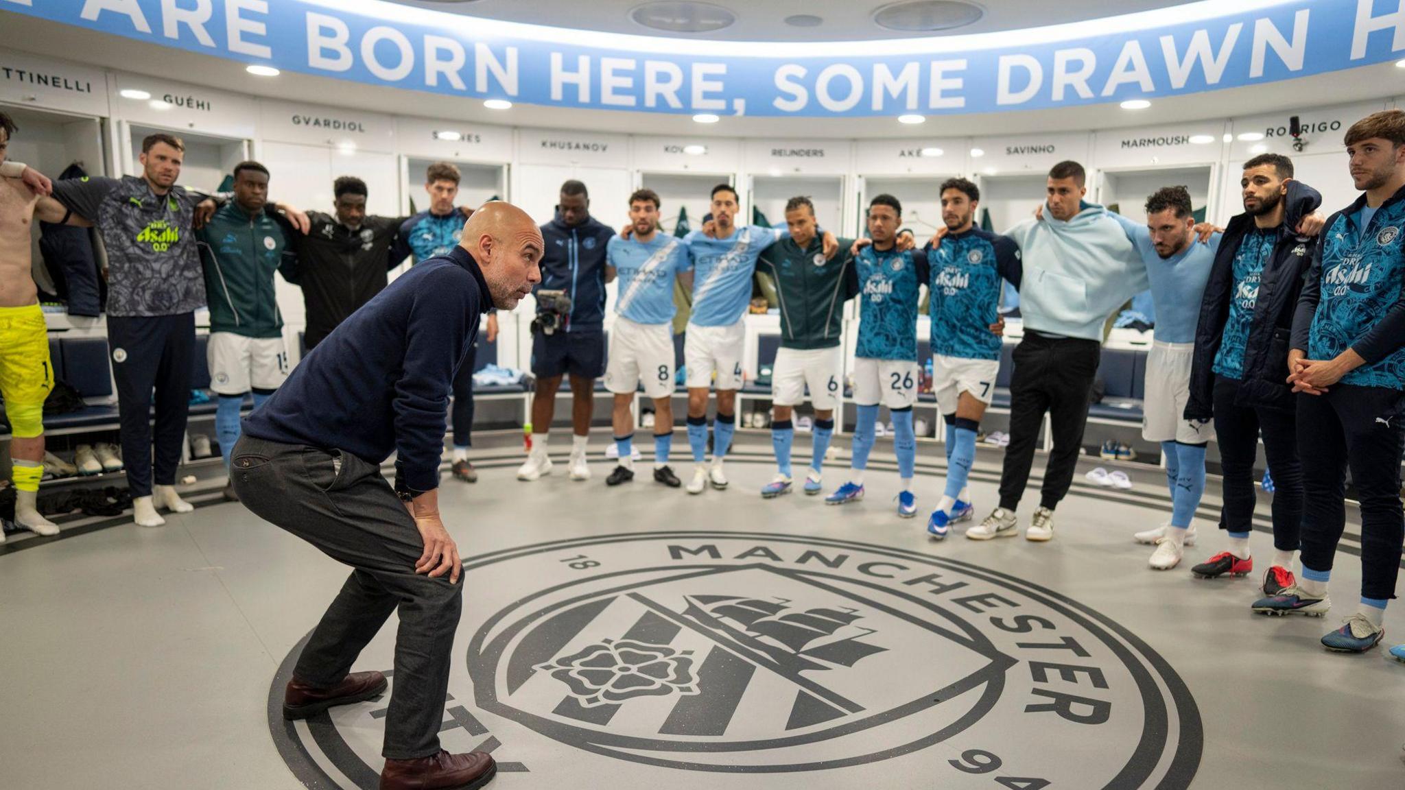 Pep Guardiola addresses his players, with his hands on his knees