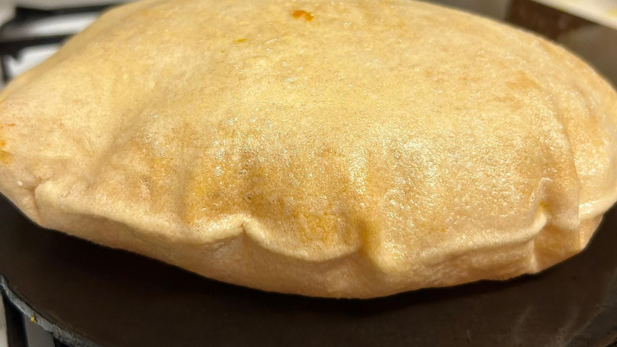 Dhal Puri, a light golden-coloured flatbread that is stuffed with seasoned ground chickpeas, on a black cast iron plate.