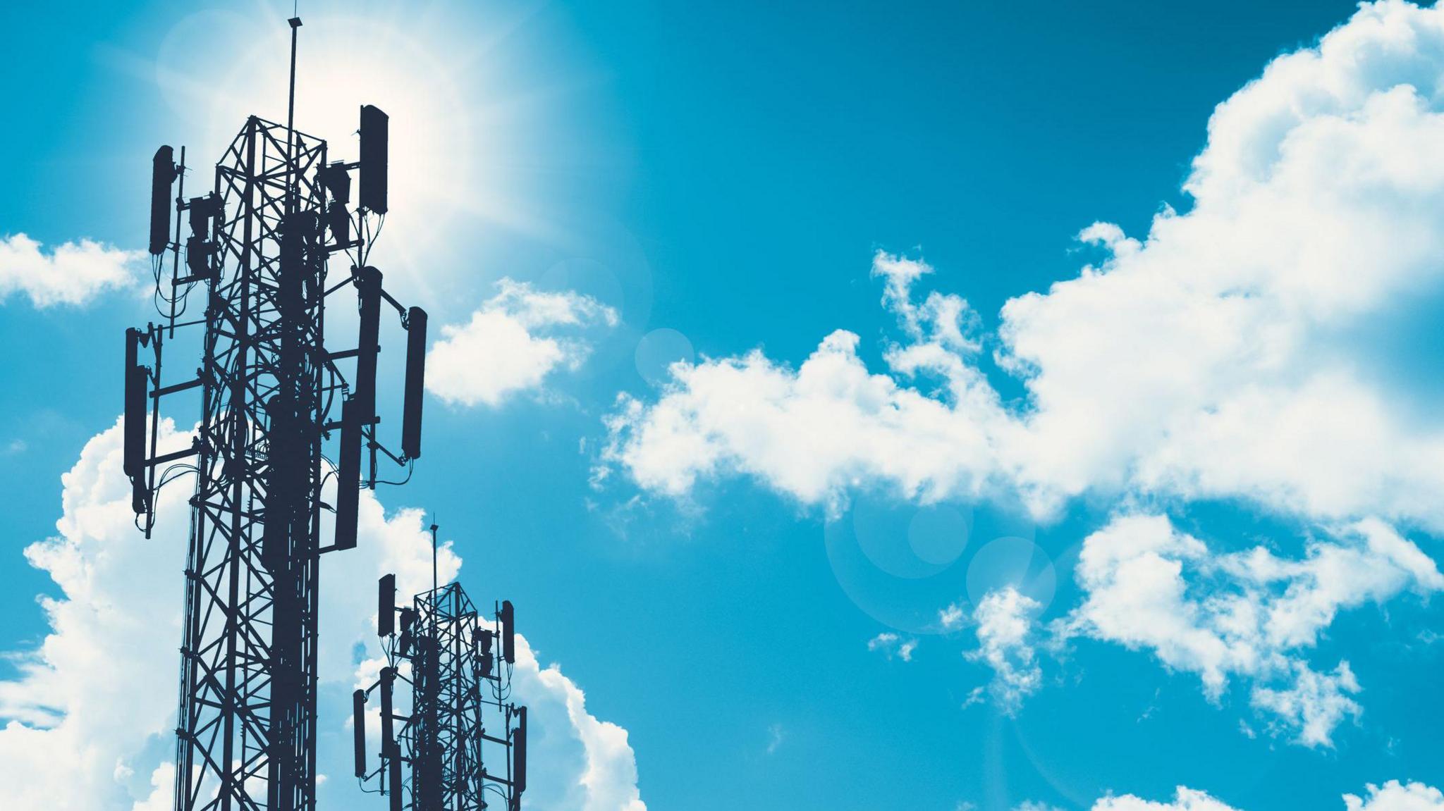 A huge communication tower against the backdrop of a blue sky with white clouds in it. 