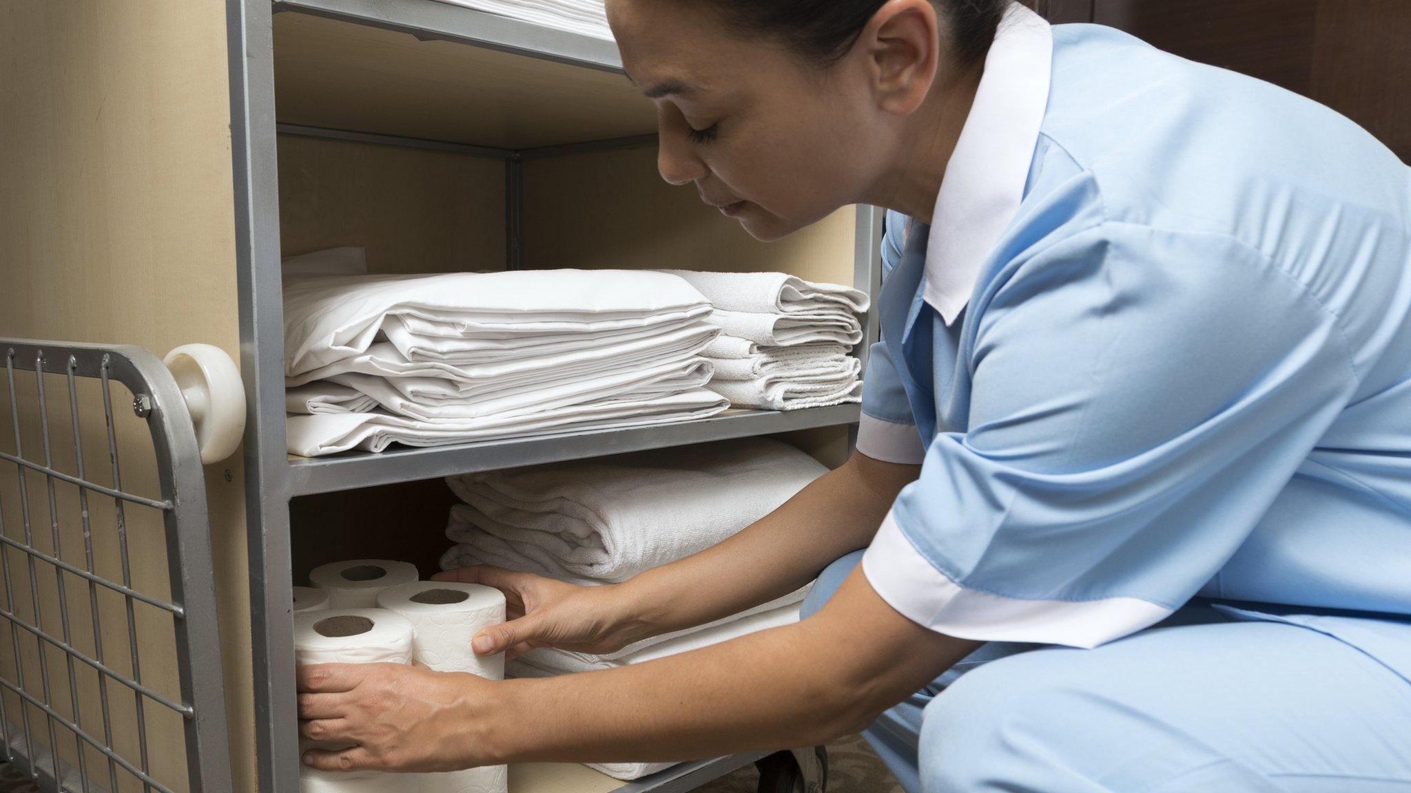 Hotel maid sorting towels and toilet paper