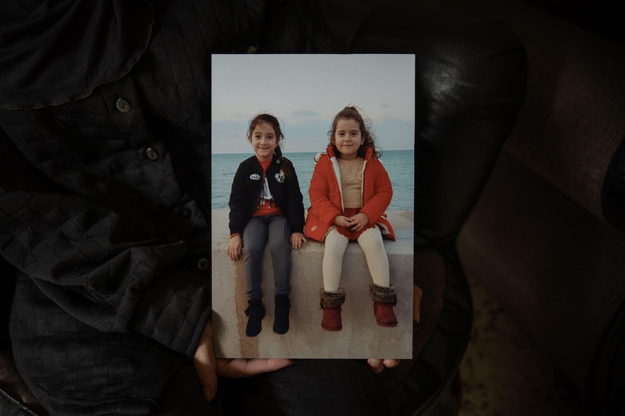 Rihab holds a picture of her daughters Tia and Naya at the water's edge in Beirut.