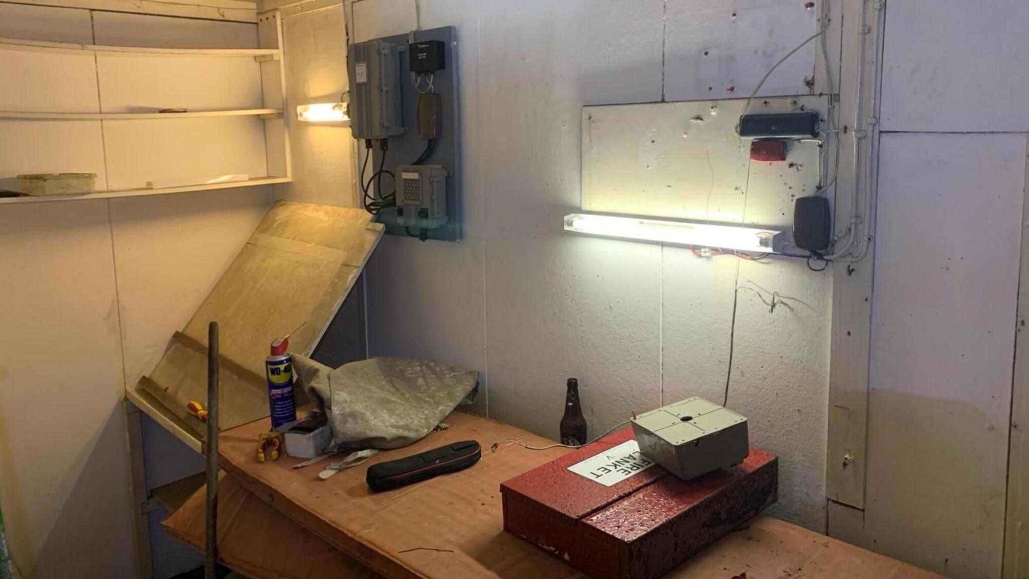 The interior of the bunker, with a desk, shelving and strip light.