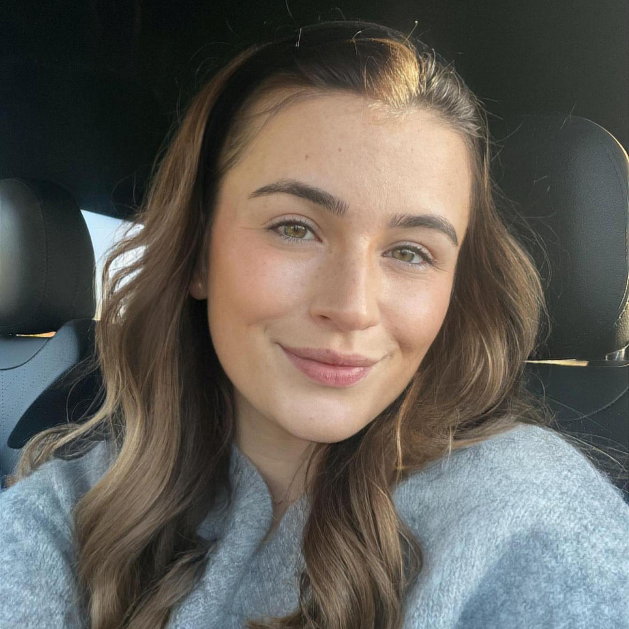 Holly May Arnott with long light brown hair, sitting in her car