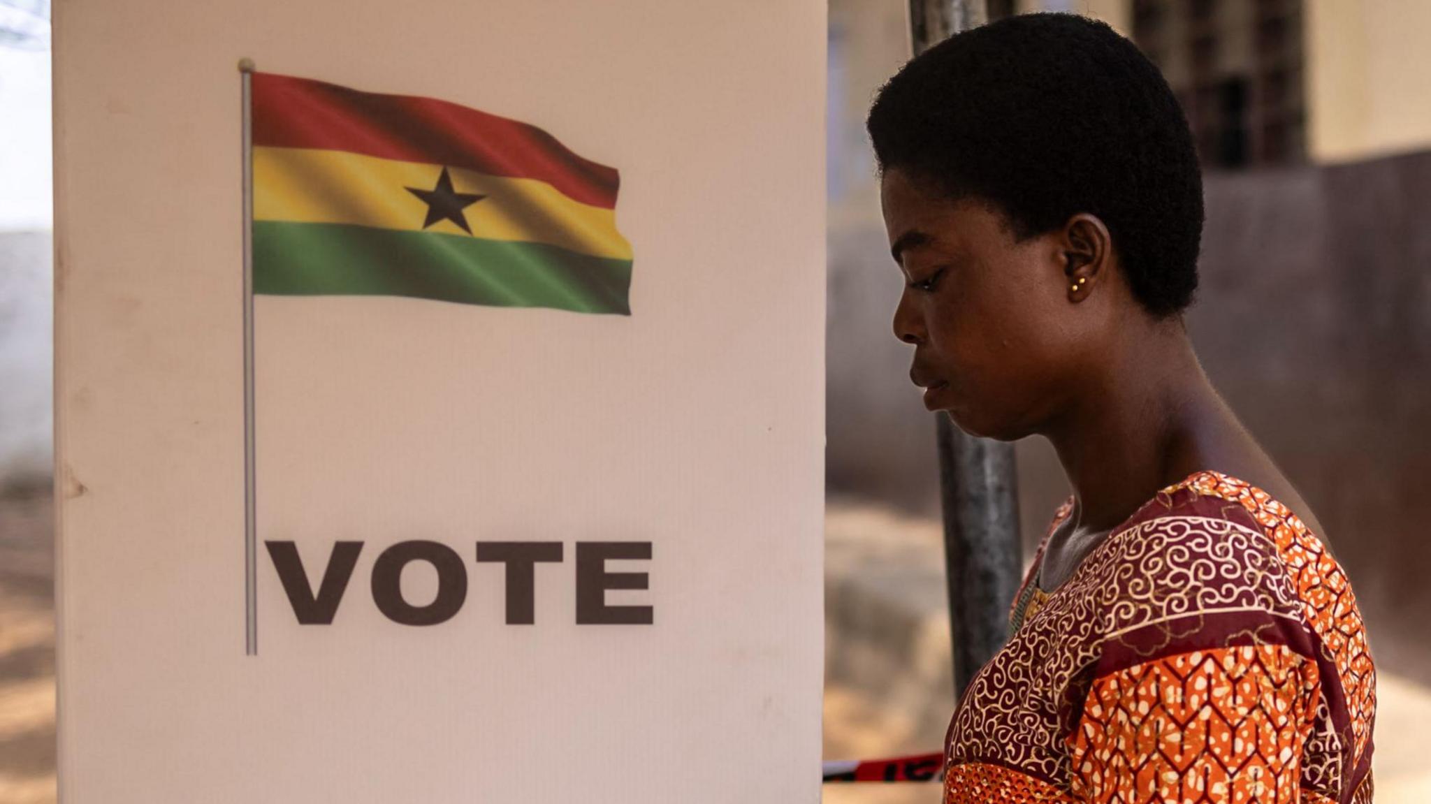 A general view of a Ghana flag on a voting booth as a woman casts her vote at a school in the Ayawaso Wuogon neighborhood of Accra.