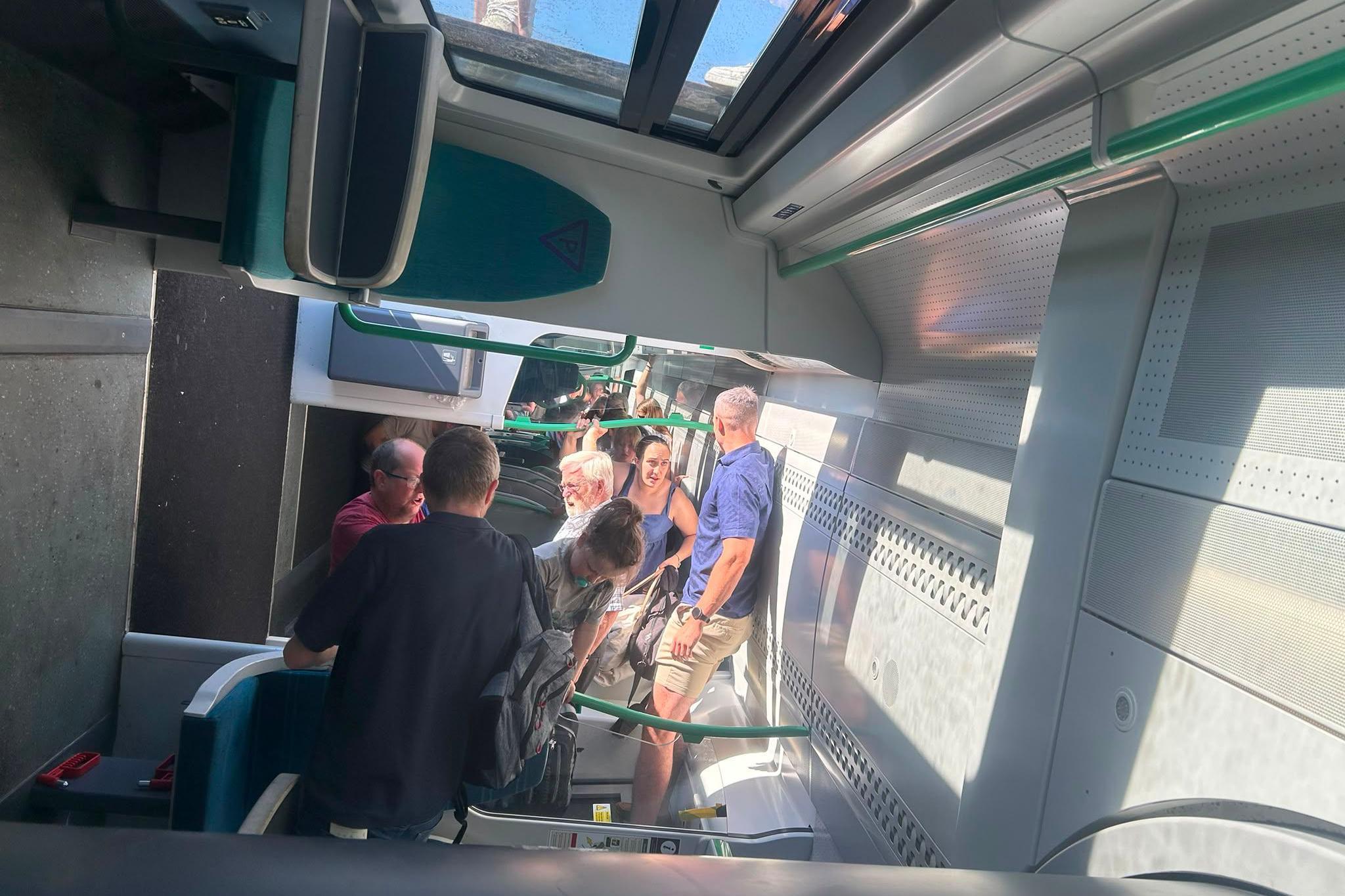 A train carriage on its side with people standing on the walls of the train.