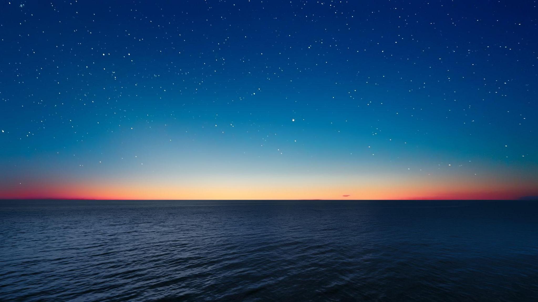 Field of stars in a deep blue sea above and even deeper blue ocean