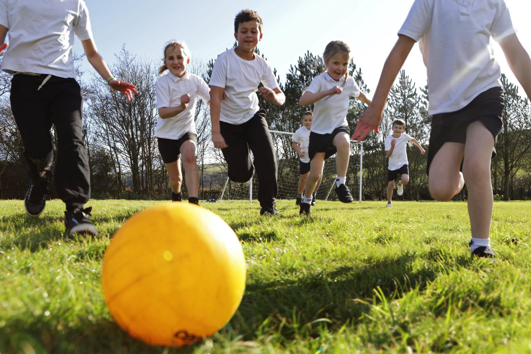 Children chasing a ball in PE class