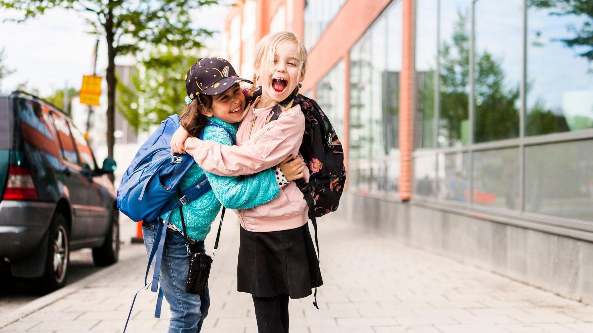 Girls hugging and laughing by school.