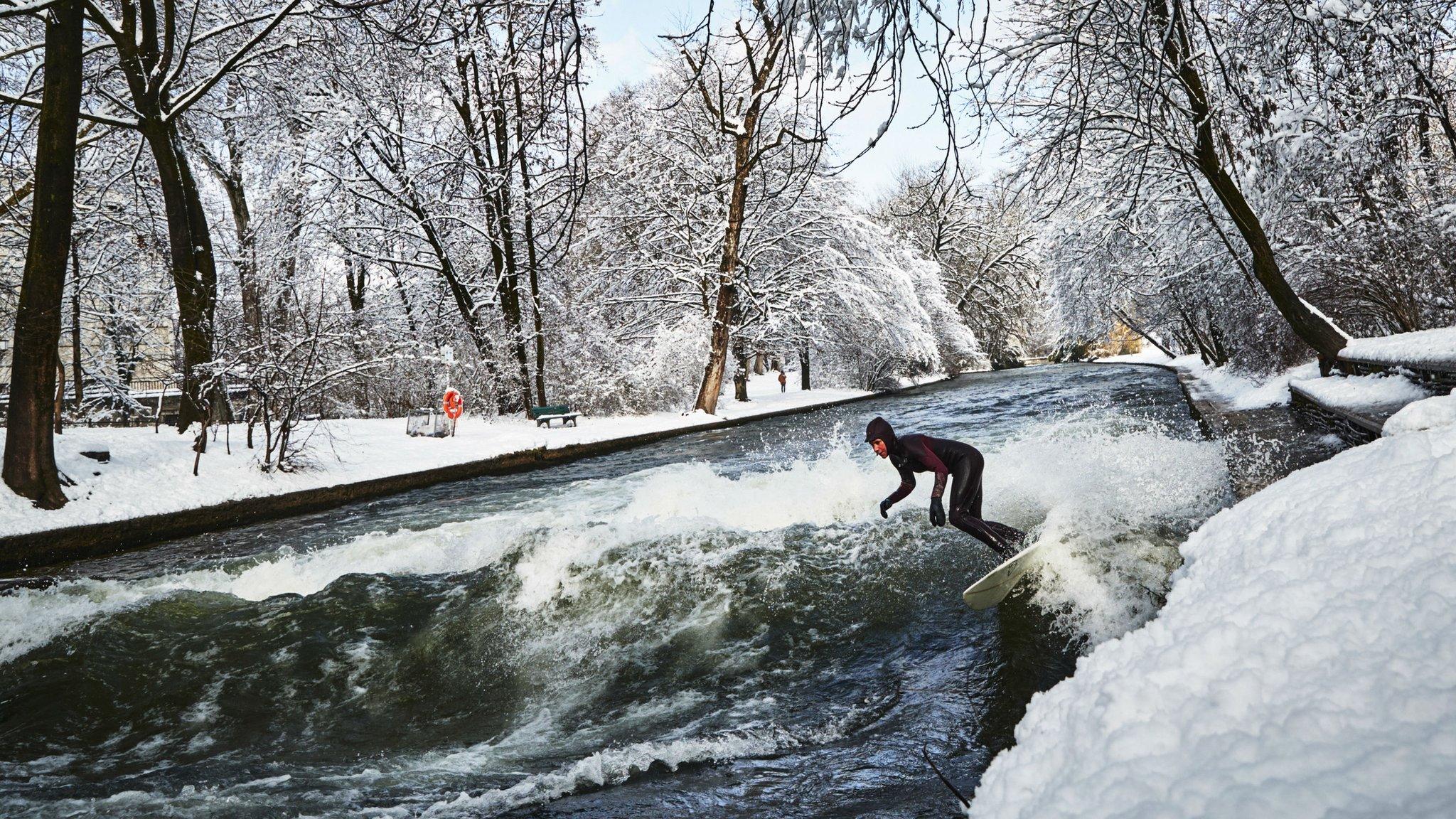 A surfer rides the Eisbach wave in the Englischer Garten in Munich