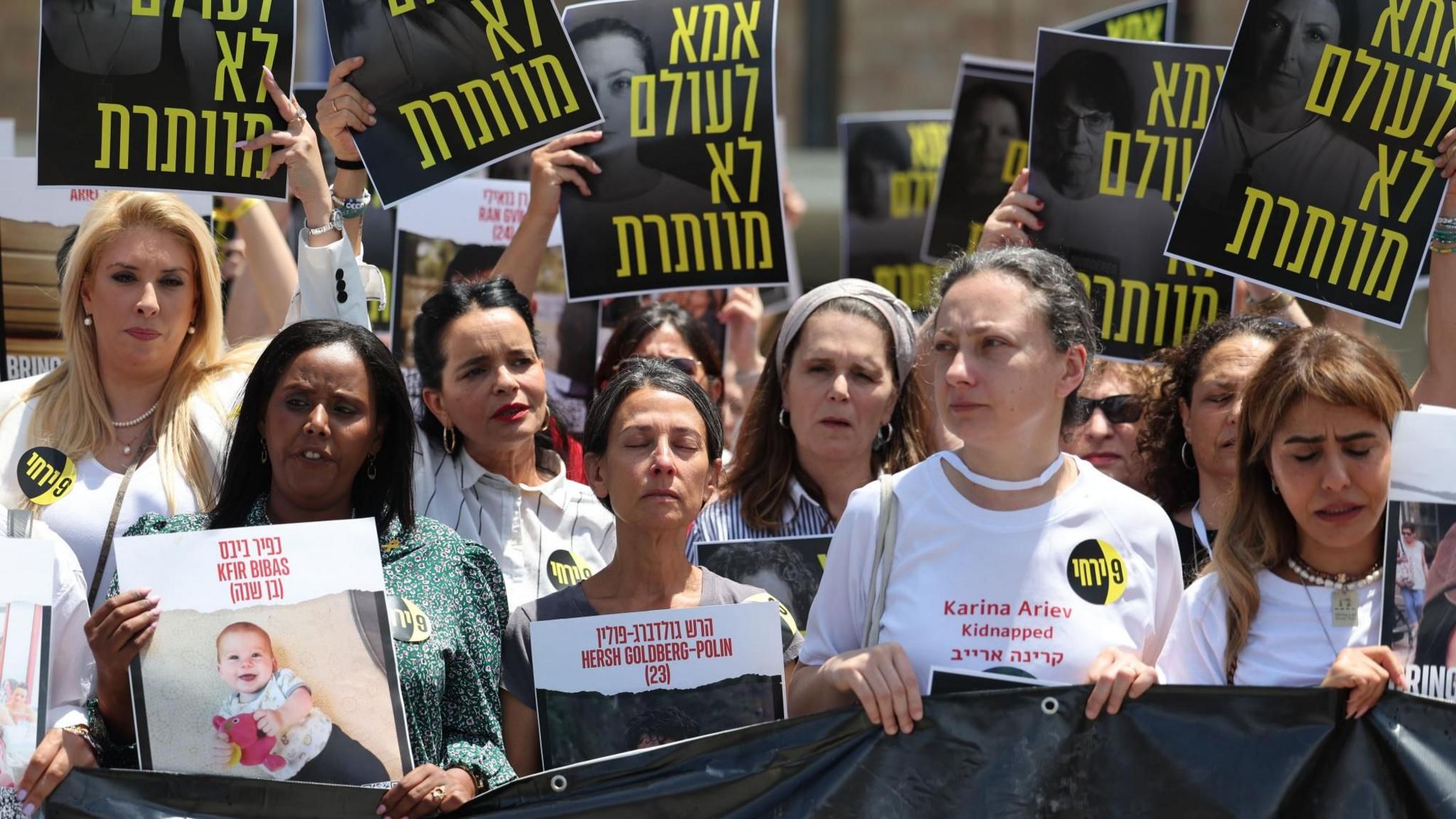 Mothers of Israeli hostages held by Hamas in Gaza hold a sign in Hebrew reading "A mother never gives up", at a protest calling on the Israeli government to agree a hostage release deal, in Jerusalem (8 July 2024)