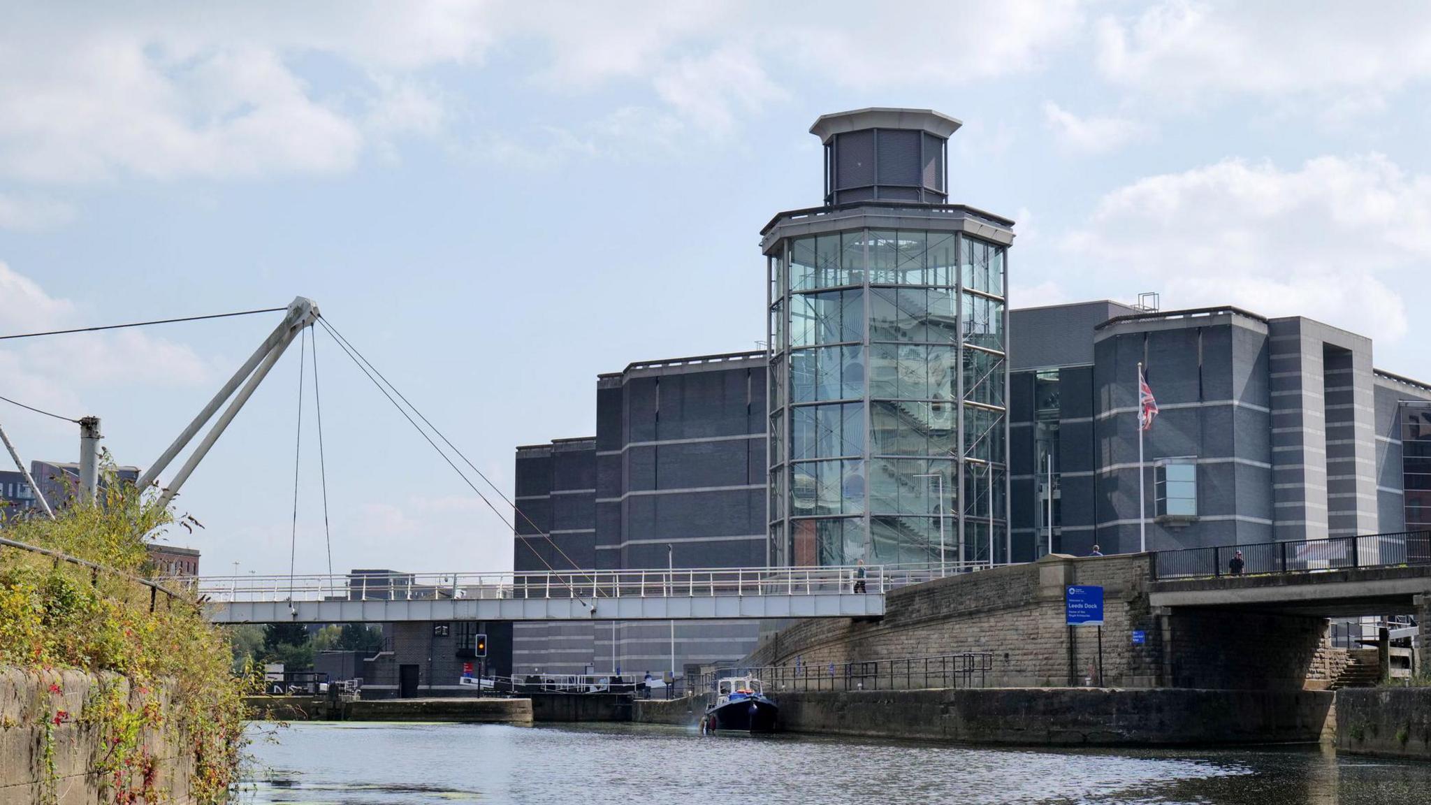 Royal Armouries in Leeds, a large modern building built adjacent to the river with a pedestrian bridge across the water