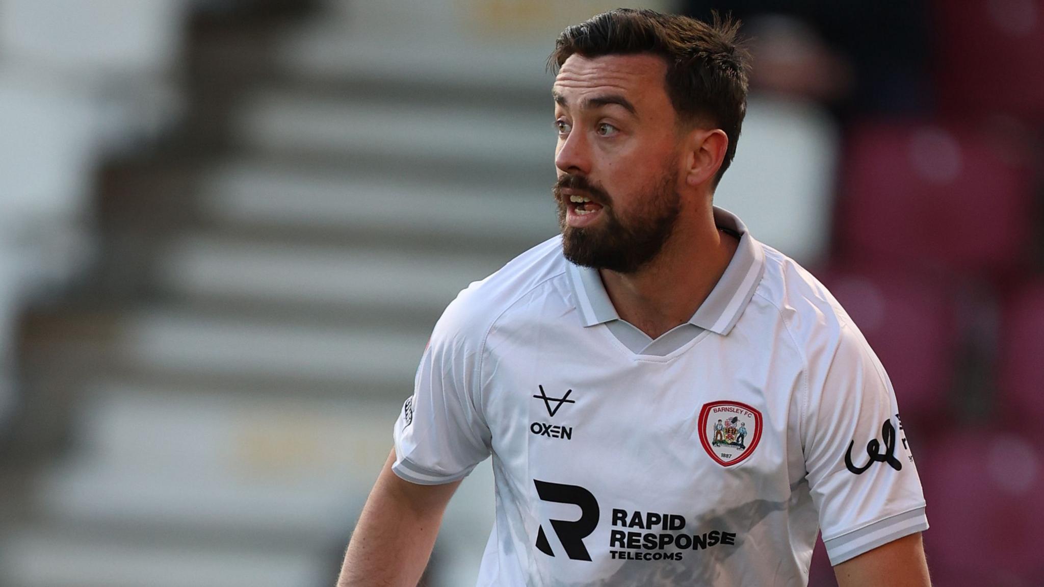 Eoghan O'Connell in action for Barnsley wearing a white away jersey