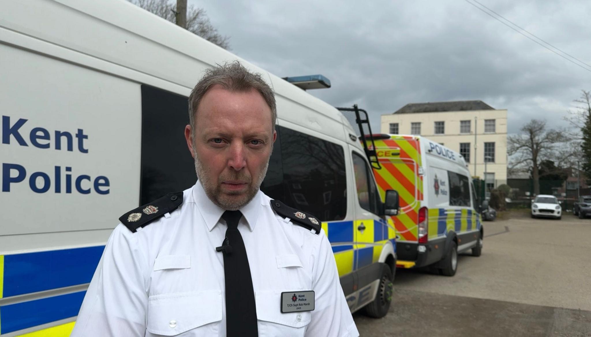 Chief Superintendent Rob Marsh is standing outside two police vans at Kent Police headquarters in Maidstone