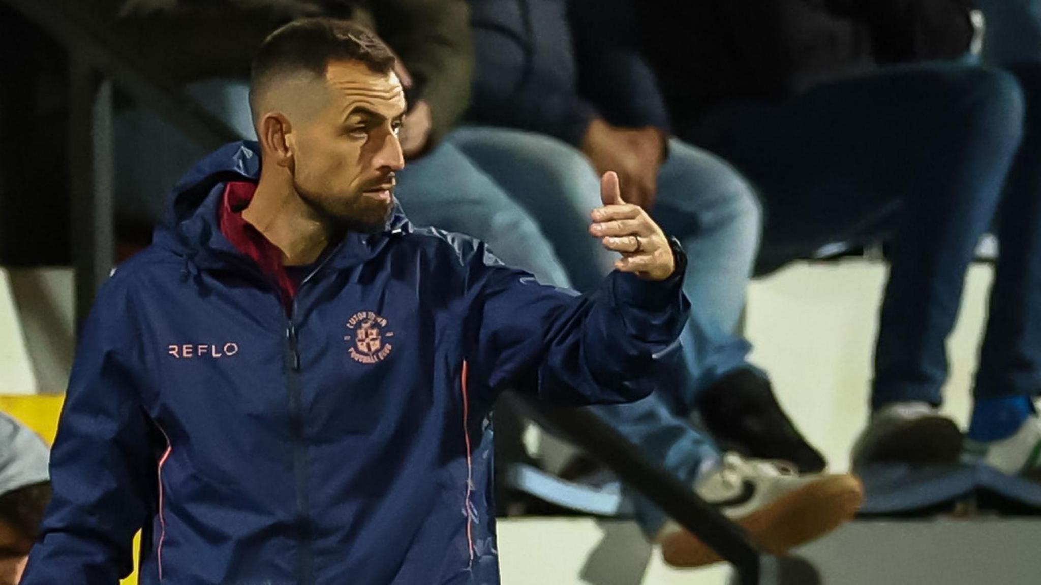 Alex Lawless sends out messages and directions to the players during Luton's game against Cambridge
