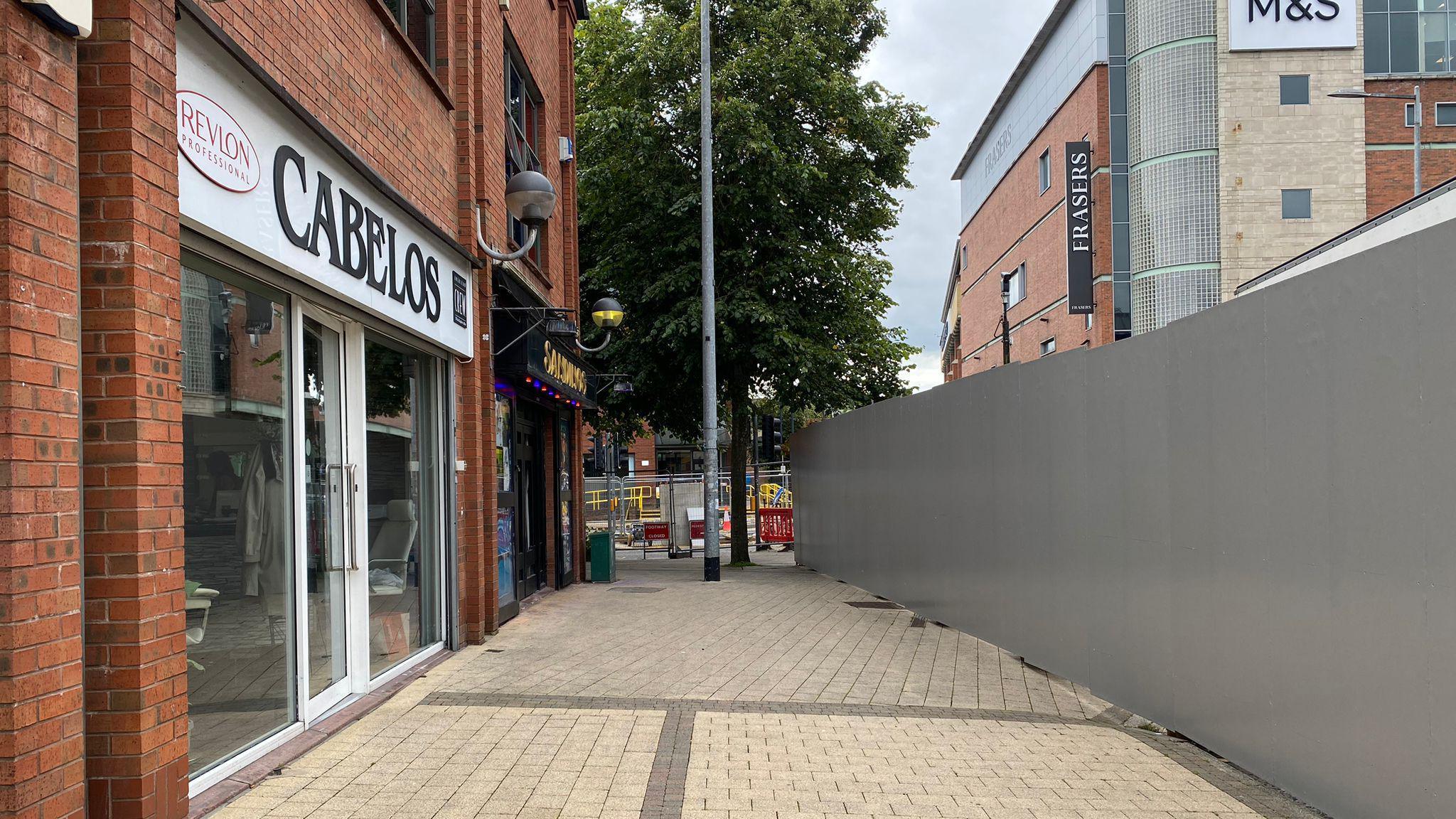 The exterior of a hair salon and pub on Derry's Foyle Street. A barrier closing off the road to traffic can be seen in the foreground