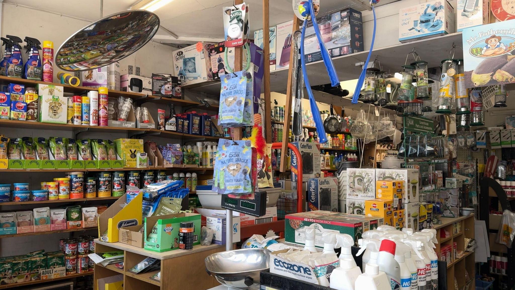 A general view of the hardware shop. The shelves are full of DIY supplies and household items, including pet food, cleaning spray, antifreeze, dog treats and bird feeders.