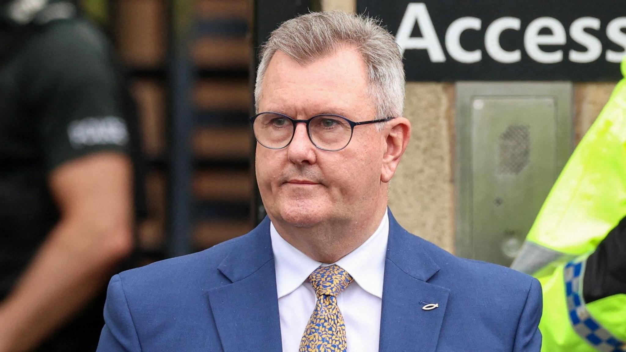 Jeffrey Donaldson. He has short grey hair, wearing glasses, a blue blazer, white shirt, blue and yellow tie, with a fish pin on his lapel.